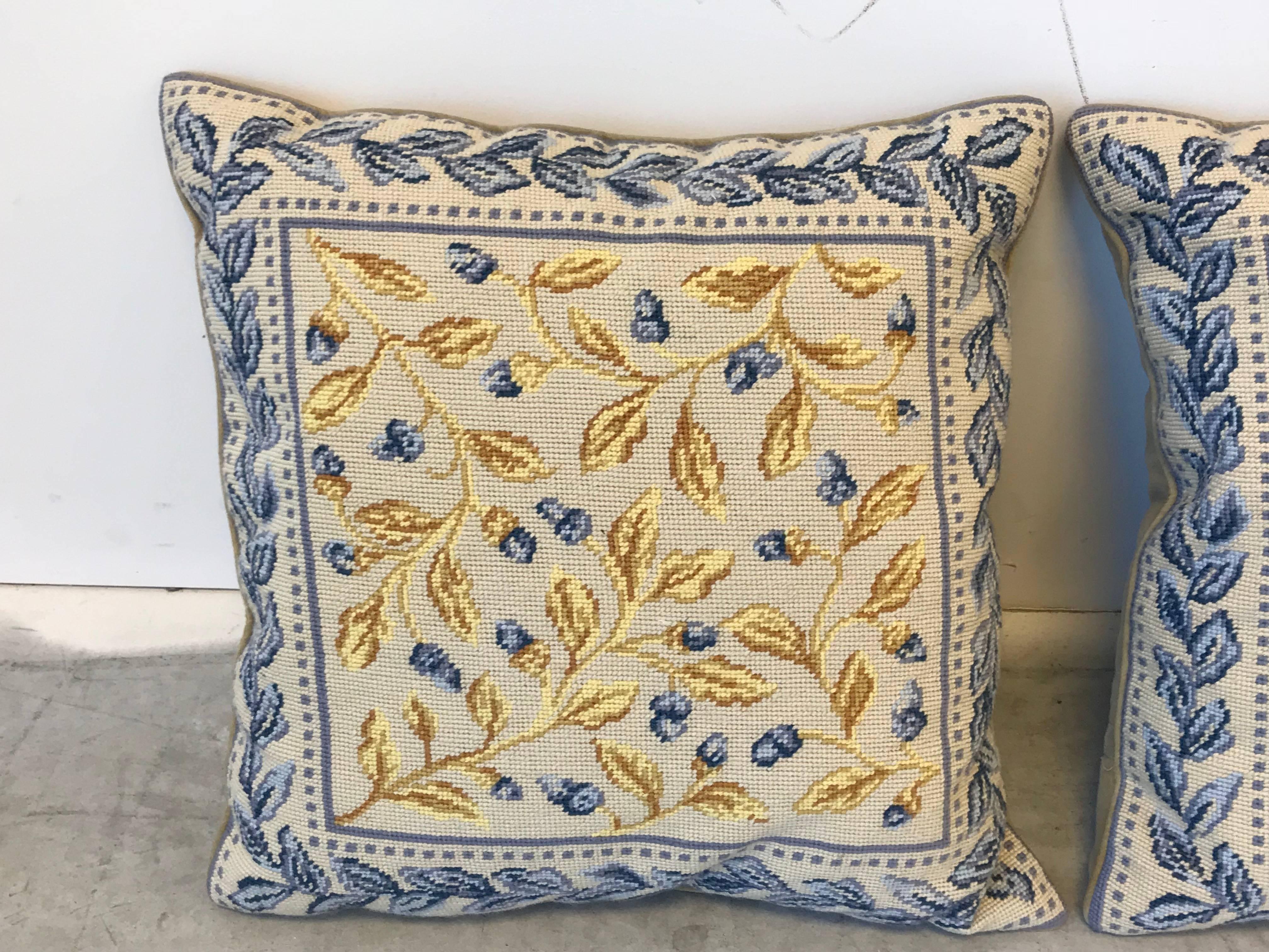 Offered is a stunning pair of 1970's needlepoint pillows. Each pillow has a blue and yellow floral motif, with a beige background. Velvet backside, with zipper. Down fill insert included. 
