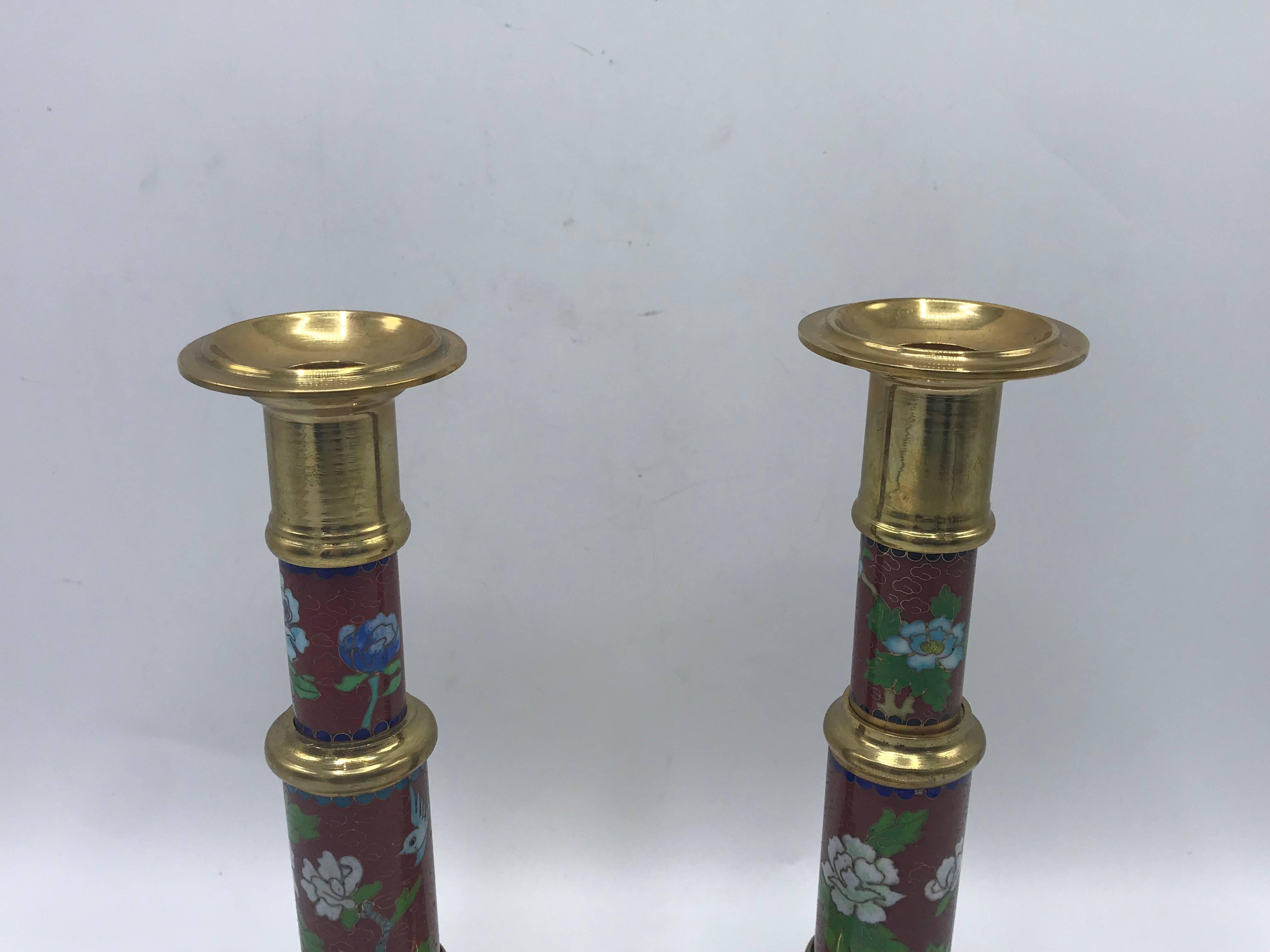 Listed is a beautiful, pair of 1960s Cloisonné candlesticks. Red and blue enamel with a mirrored floral motif on each. Holds a standard, round candlestick. Heavy.