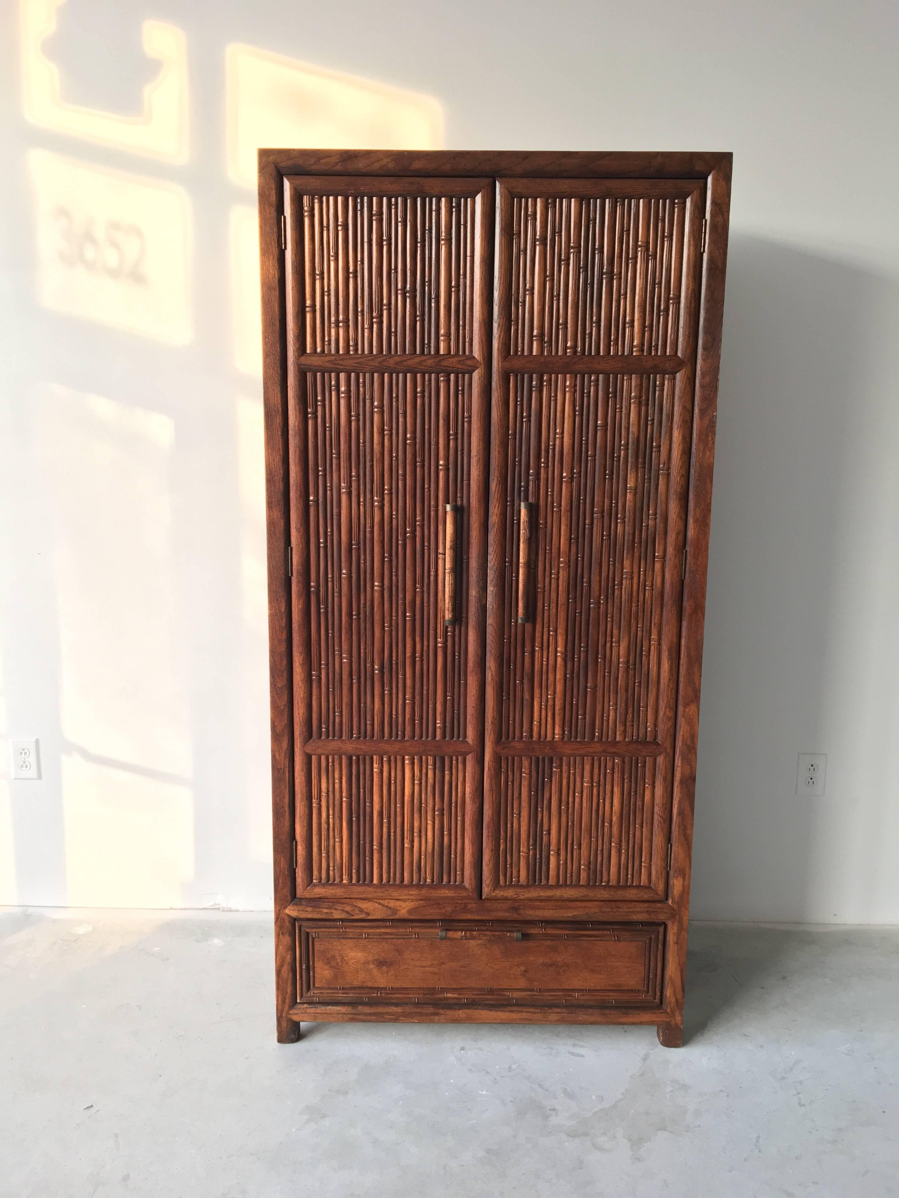 Offered is a rare and fabulous, Century Furniture faux-bamboo armoire. This piece is from their commemorative, bicentennial Candia Collection line, 1975-1976. It's a substantial piece, made of solid oak. The interior has a six cube shelving unit,