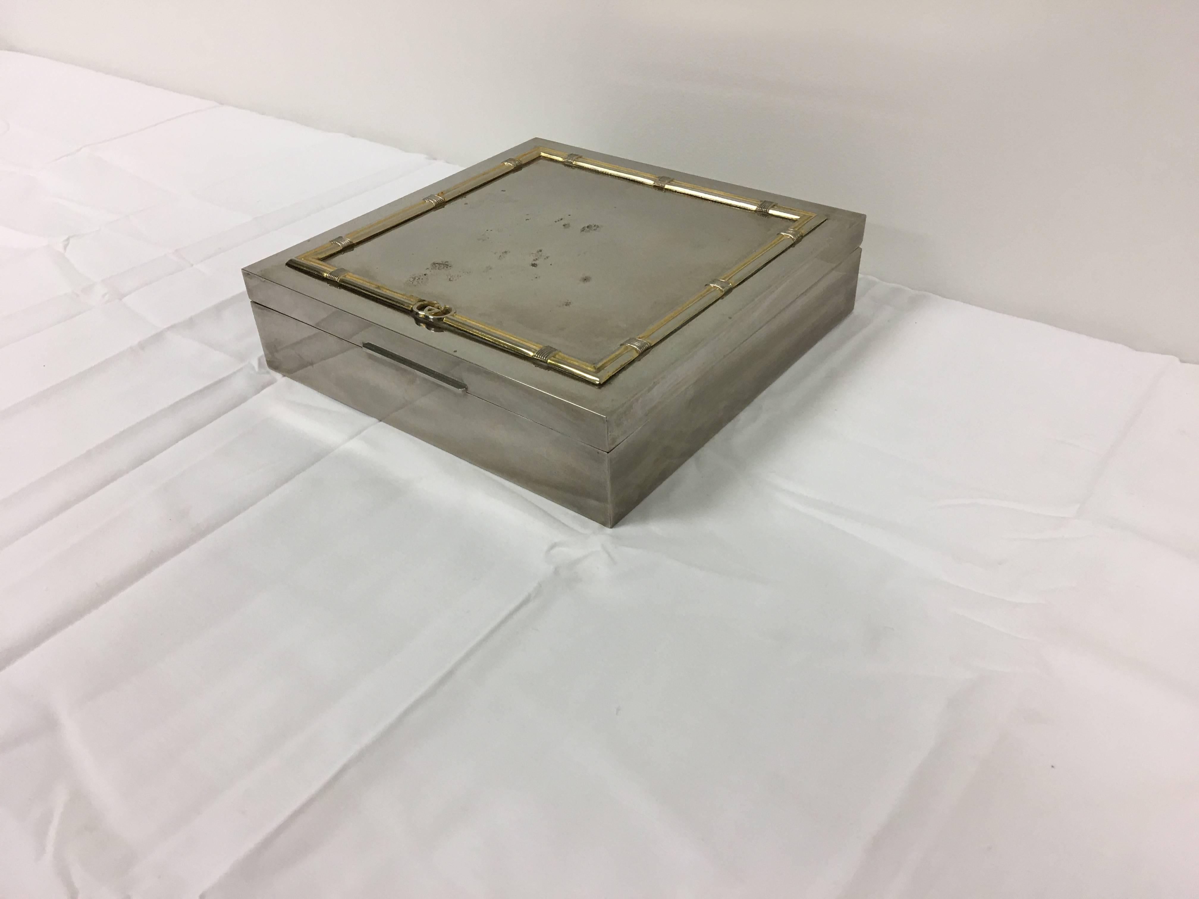A fabulous, 1960s Gucci humidor cigar box. Silver and brass-plated, with a faux-bamboo border along the top. 

Marked: Gucci. Italy.