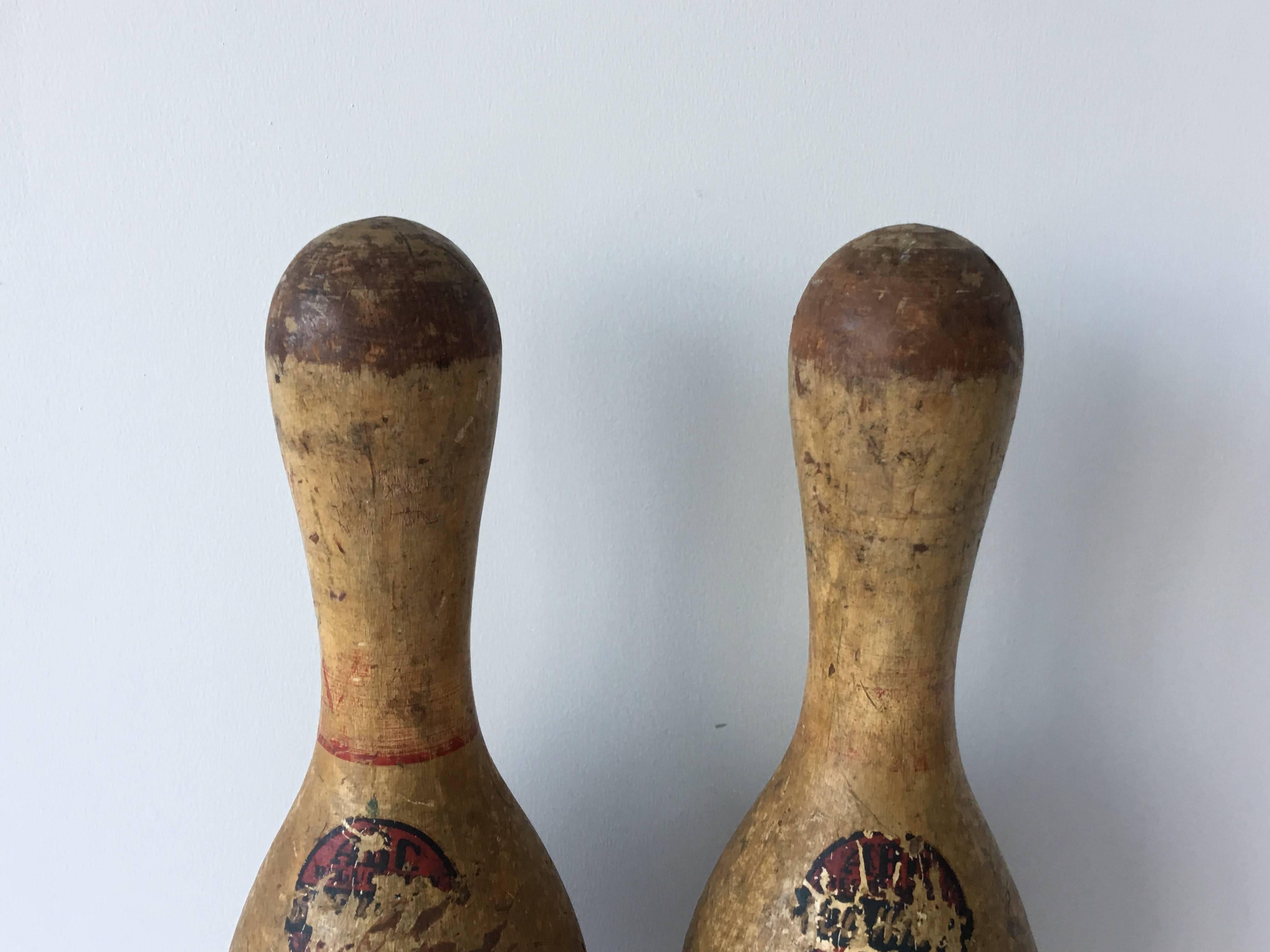 Antique pair of wooden bowling pins. Rustic and Primitive touch. Old logo stickers on each, worn with age.