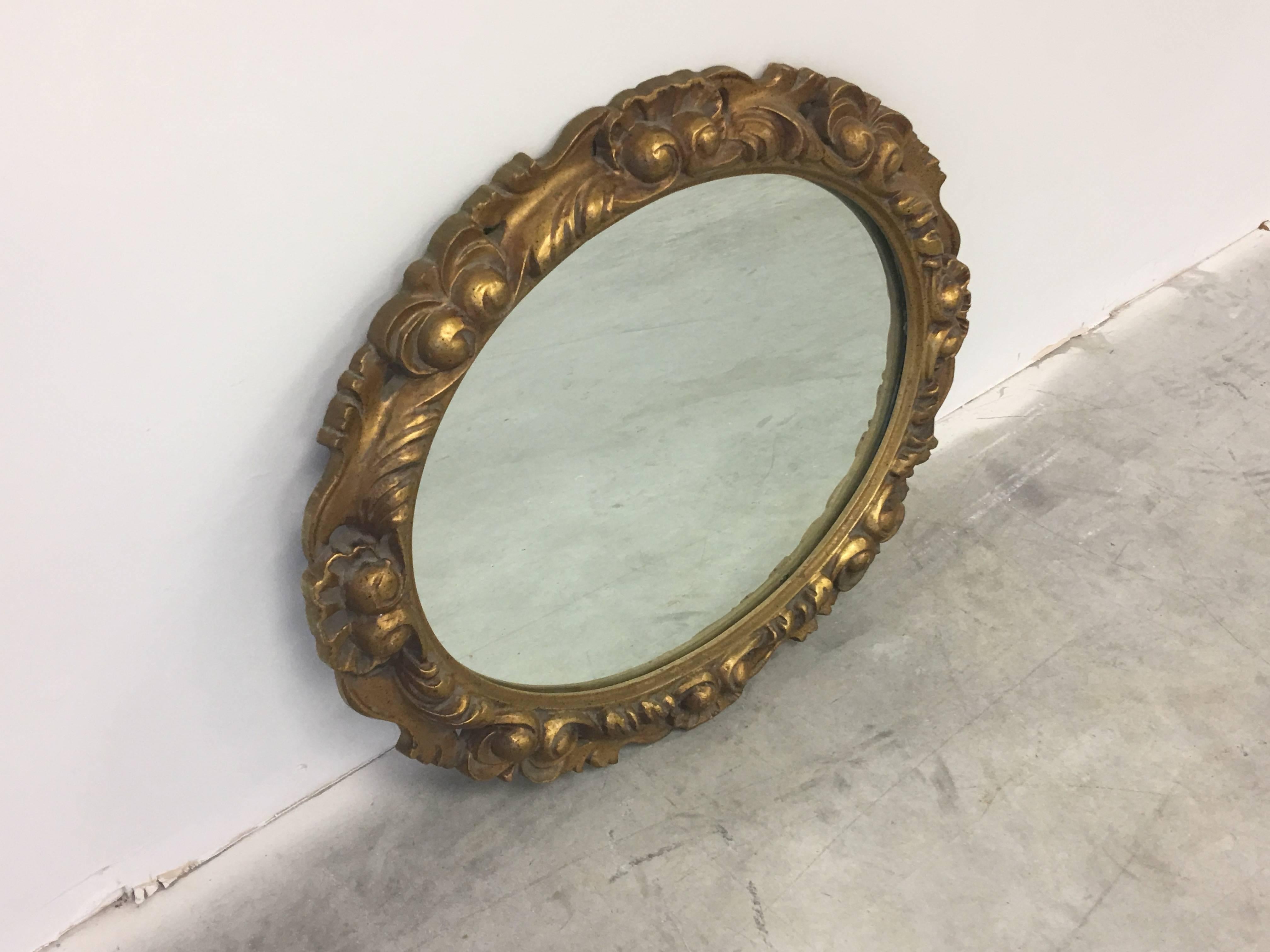 An immaculate, 19th century style oval gilt mirror with heavy detailing along the border. Solid wood. Horizontal and vertical hanging.
 