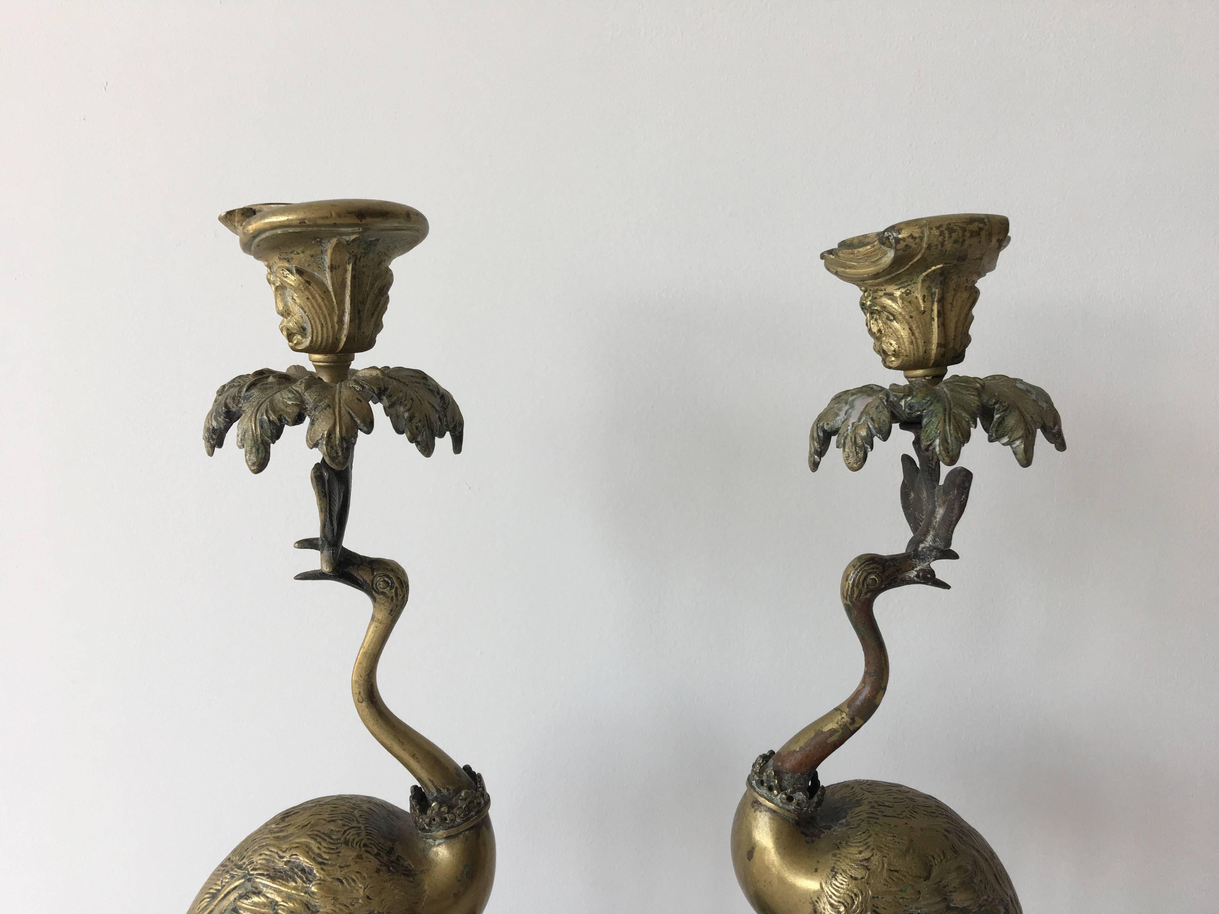 Offered is an absolutely stunning, rare, antique 19th century pair of brass/bronze ostrich candleholders. They have beautiful detailing! Above their heads are palm trees. They are each wearing crowns around the necks. Along the base, they're