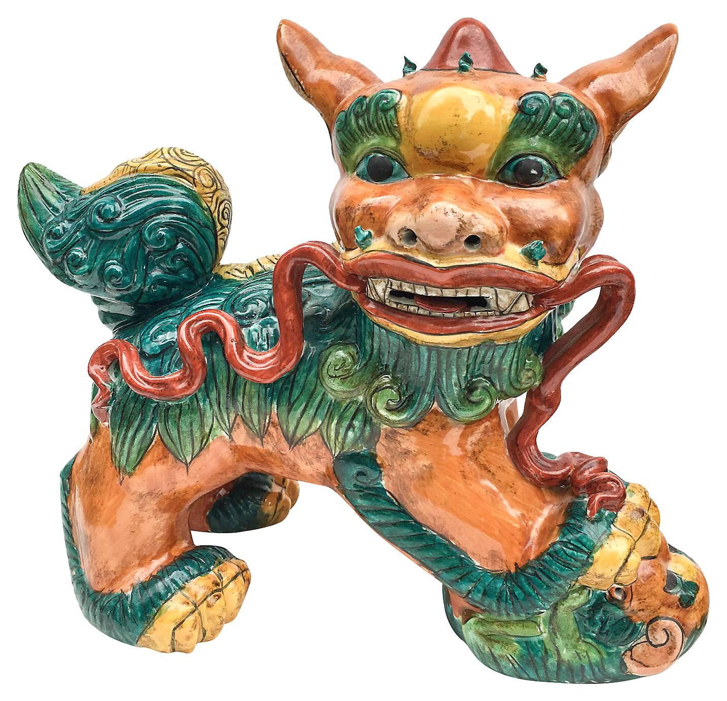 Incredibly detailed pair of brightly colored antique Chinese foo dog statues, late 19th century. Each features a gorgeous polychrome glaze in shades of warm umber, Chinese red, emerald green, and teal. Note the detail of the red ribbon running