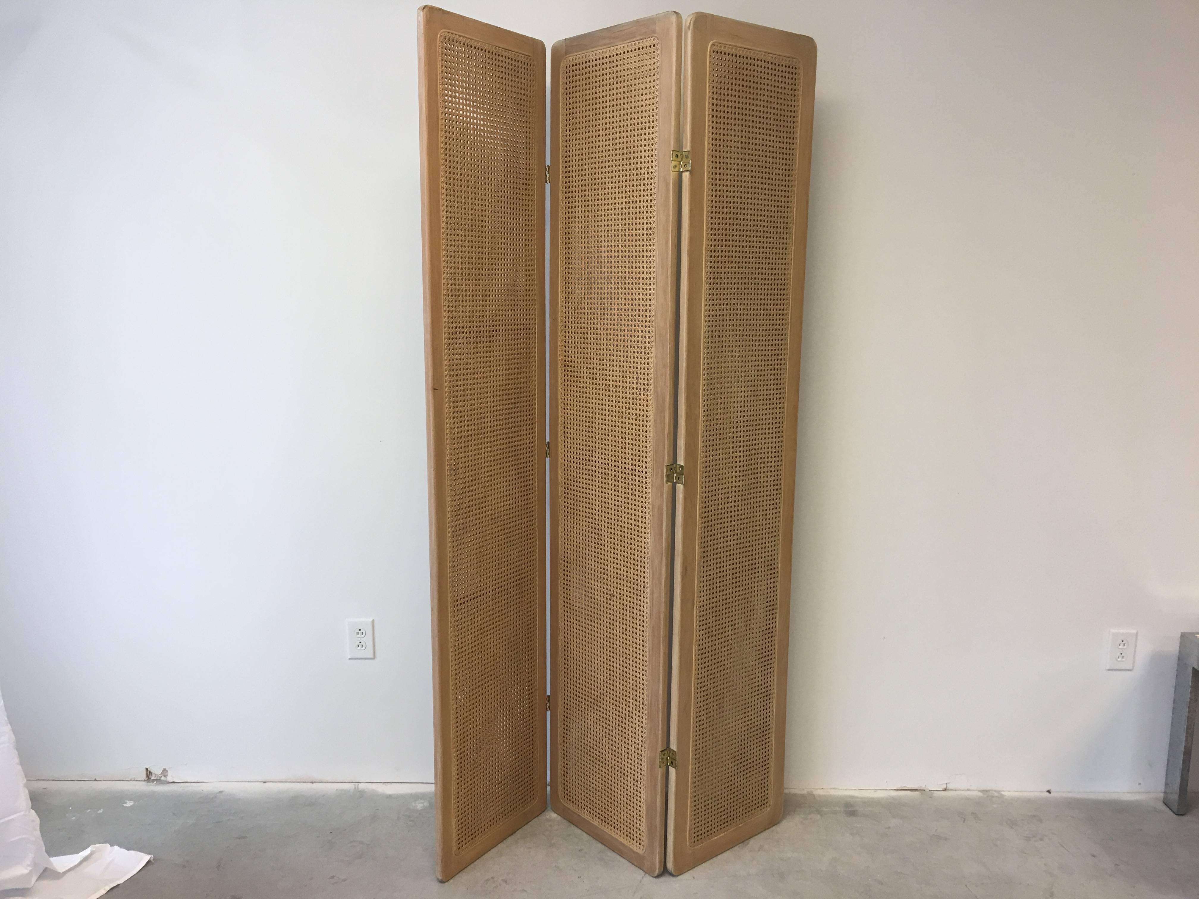 Offered is a stunning, 1950s Mid-Century Modern, Palm Beach styled three-panelled screen from woven cane and wood. 

Each panel measures 17