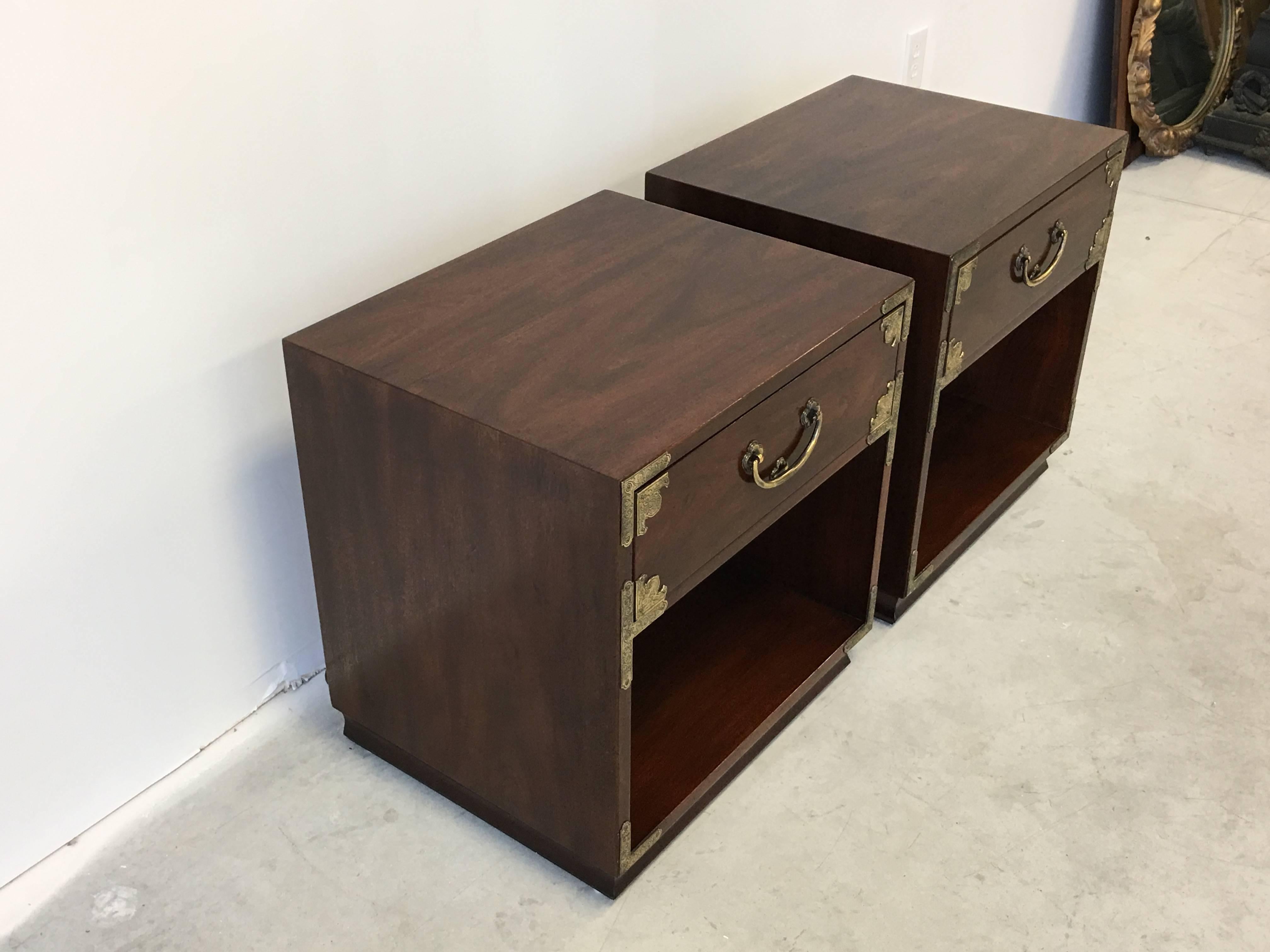 Offered is a stunning pair of Henredon, Asian style Campaign chest nightstands. Featuring, intricate brass hardware and an immaculate walnut finish. Underneath the drawer, each nightstand has a power cord with three AC outlet plugins. Convenient for