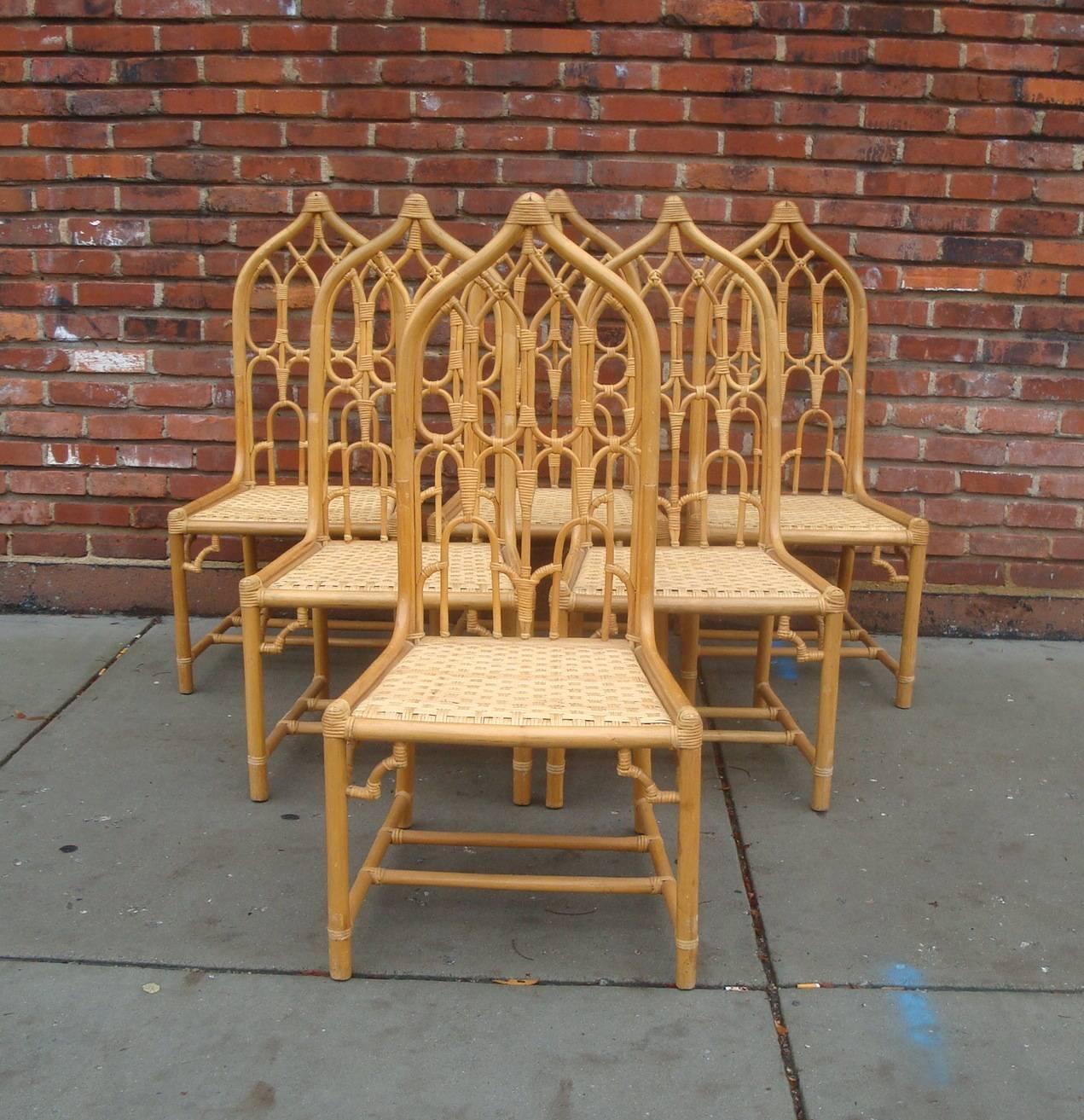 Offered is a fabulous set of six rattan bamboo dining chairs with arched arabesque cathedral high peaked backs and double stretcher bases, by McGuire. Chairs can be used with cushions if desired. Interior of seat measures 18.5" (front) and