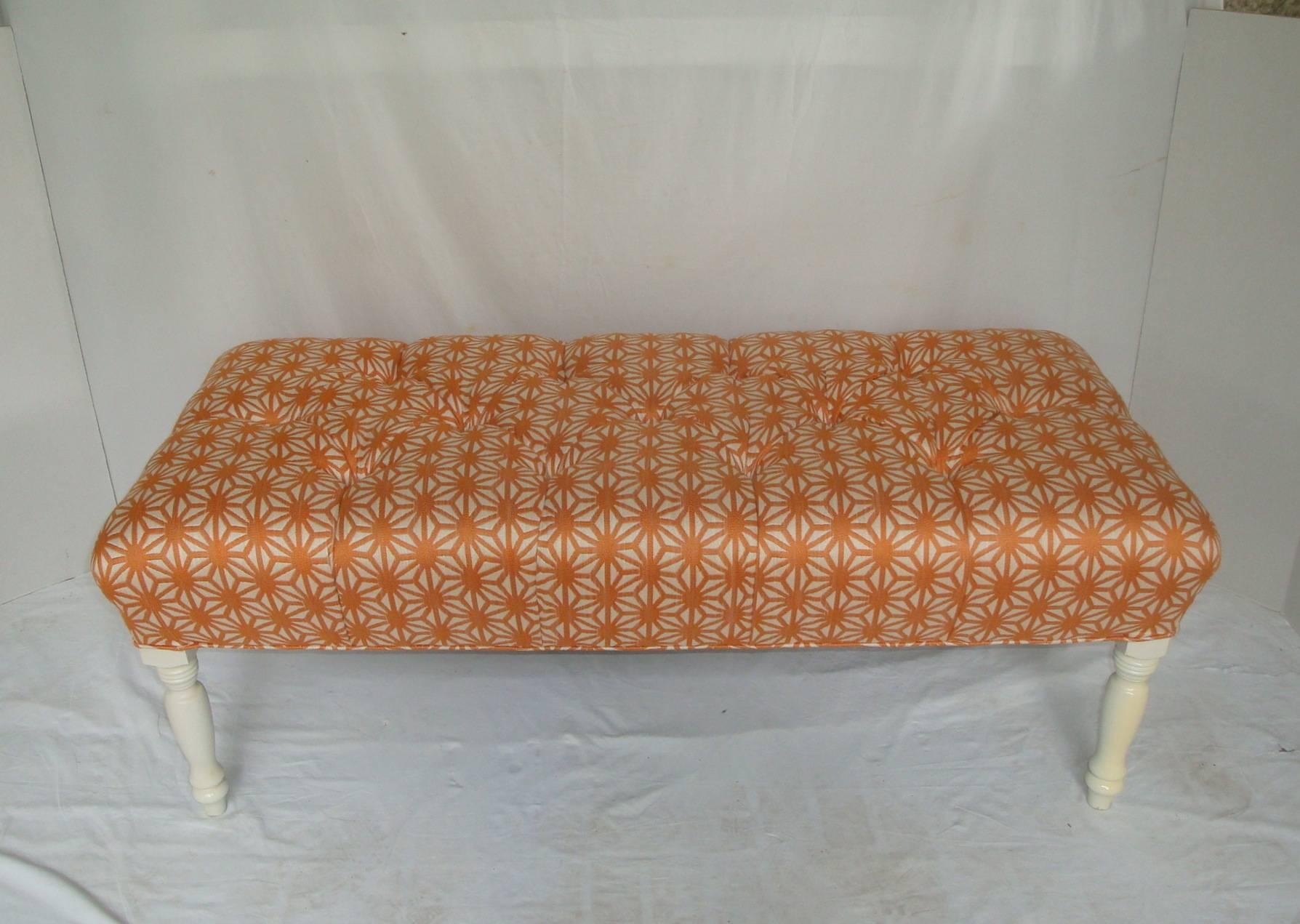 Offered is a stunning, 1960s vintage bench newly re-upholstered in a modern linen blend fabric by Thibaut, featuring a modernist orange starburst geometric pattern with deep button tufting. The curvy turned solid wood legs are finished in soft-white