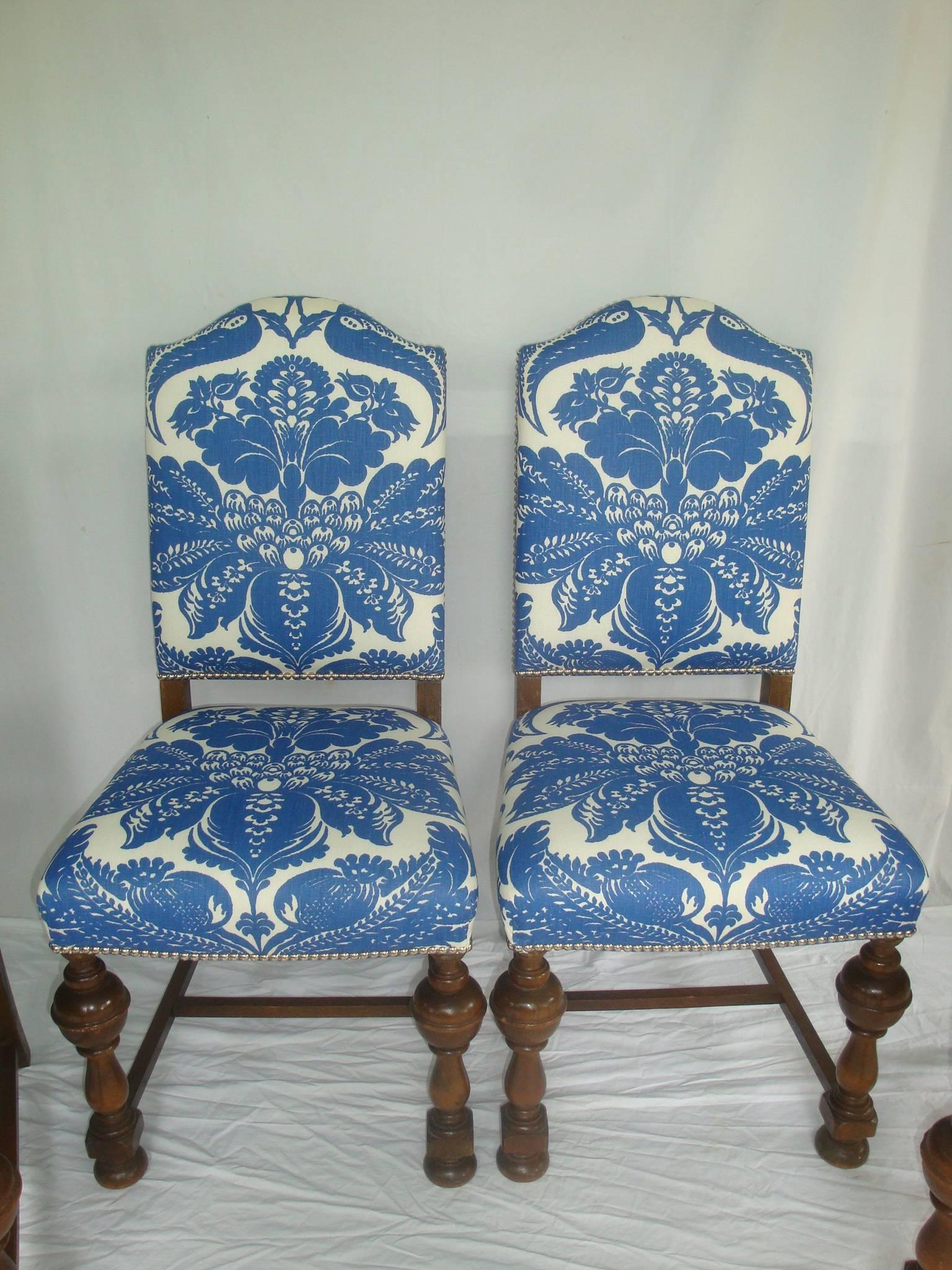 Offered is a stunning, set of four 1920s, Jacobean dark oak dining chairs with carved legs and arch top backs.

The set has recently been re-upholstered in new custom upholstery by Stroheim & Romann. The large-scale blue fabric is hand printed