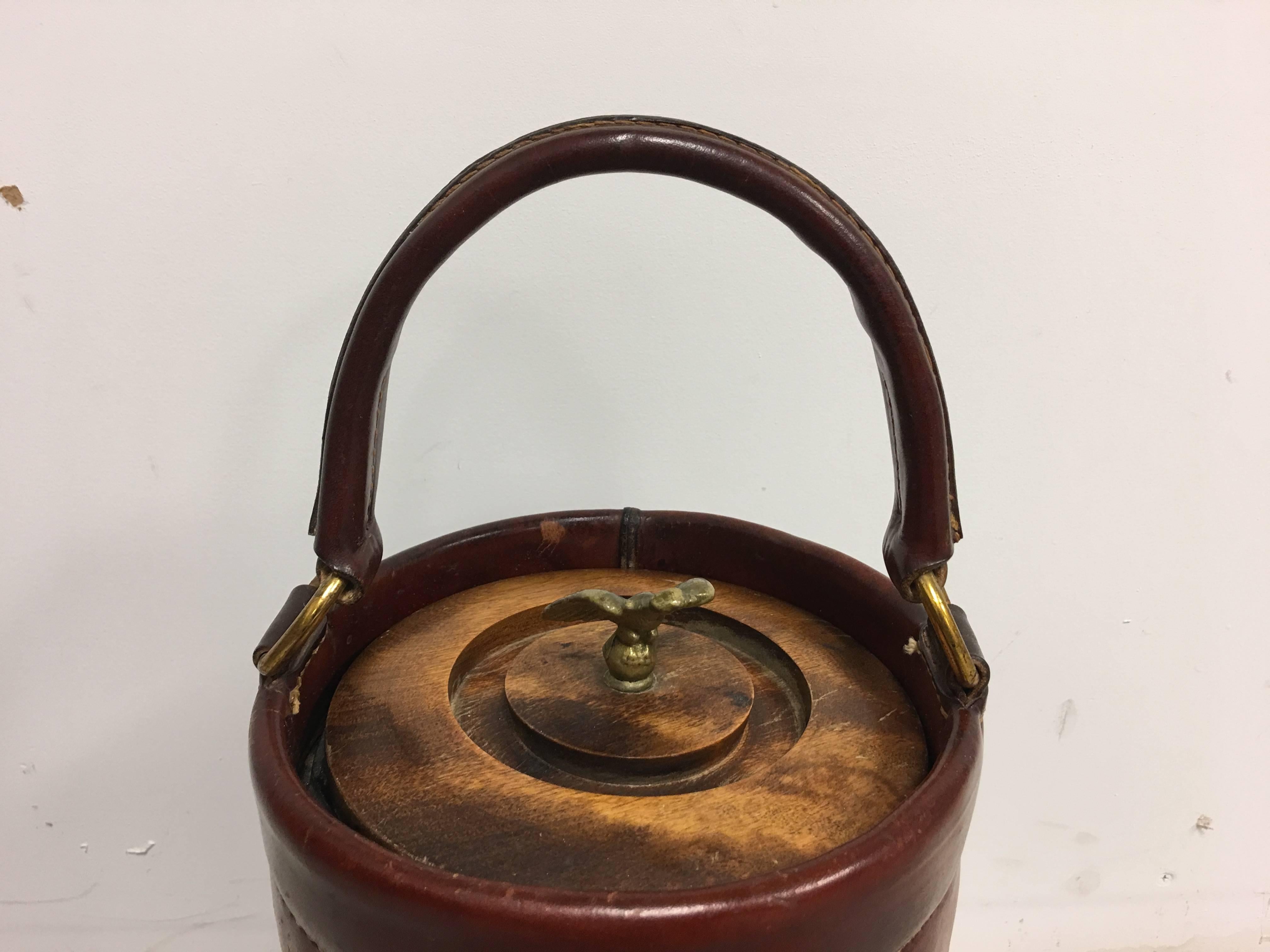 Offered is a gorgeous, large 1950s leather Loyal Papeete fire brigade ice bucket. Hand-painted fire truck on front side, seam along the backside. Brass accents, with American eagle lidded handle. Reproduction of the original fire bucket, used