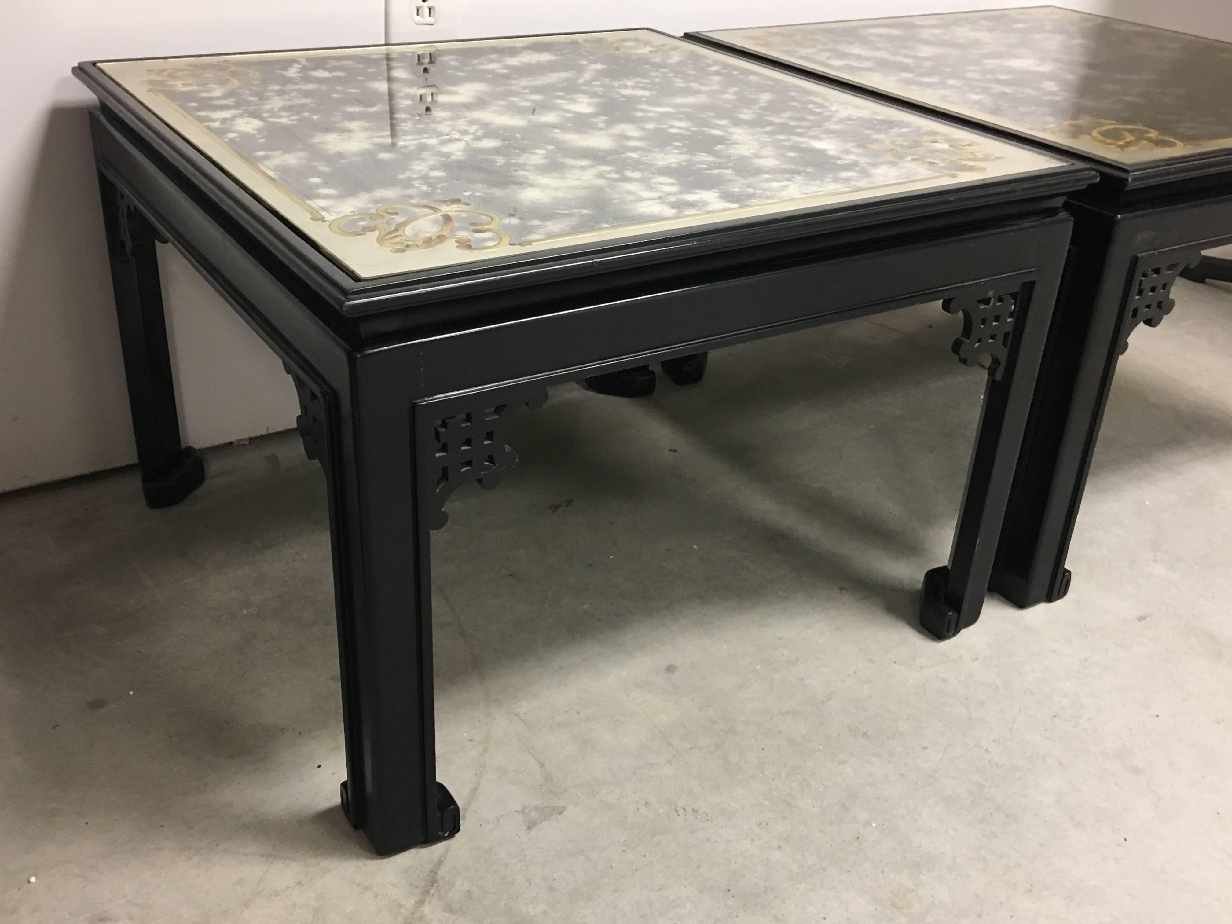 Offered is a stunning, pair of 1960s Maison Jansen black ebonized side tables with gold and silver decorated glass. The bases feature a Ming-style fretwork and footwork. Minor scratches on the glass surface, though nothing terribly noticeable.