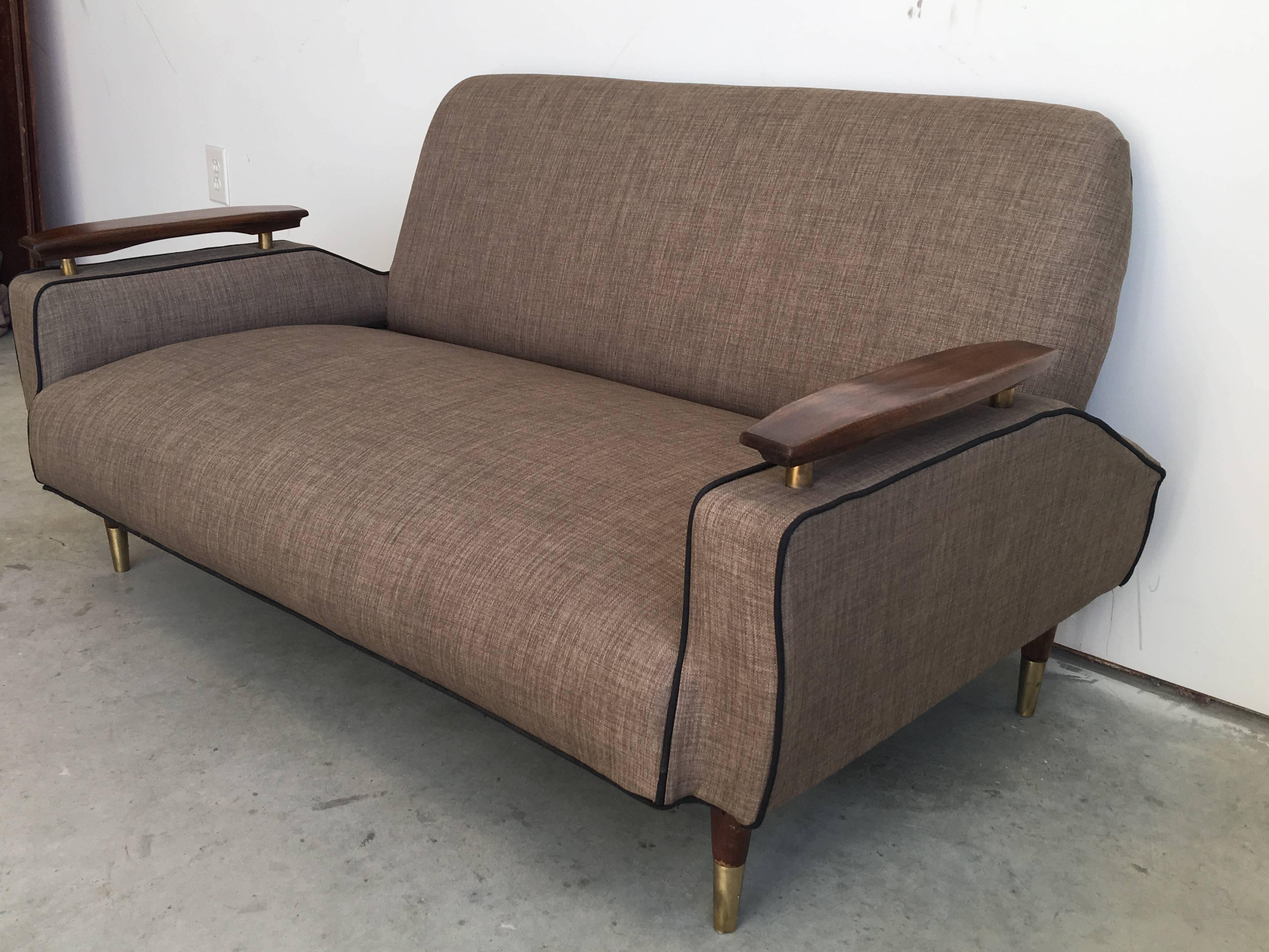 Offered is an immaculate, 1940s French deco sofa. The piece is upholstered in a tan or brown fabric, accented by floating walnut arms and brass detailing. Fabric is a coarse linen blend.