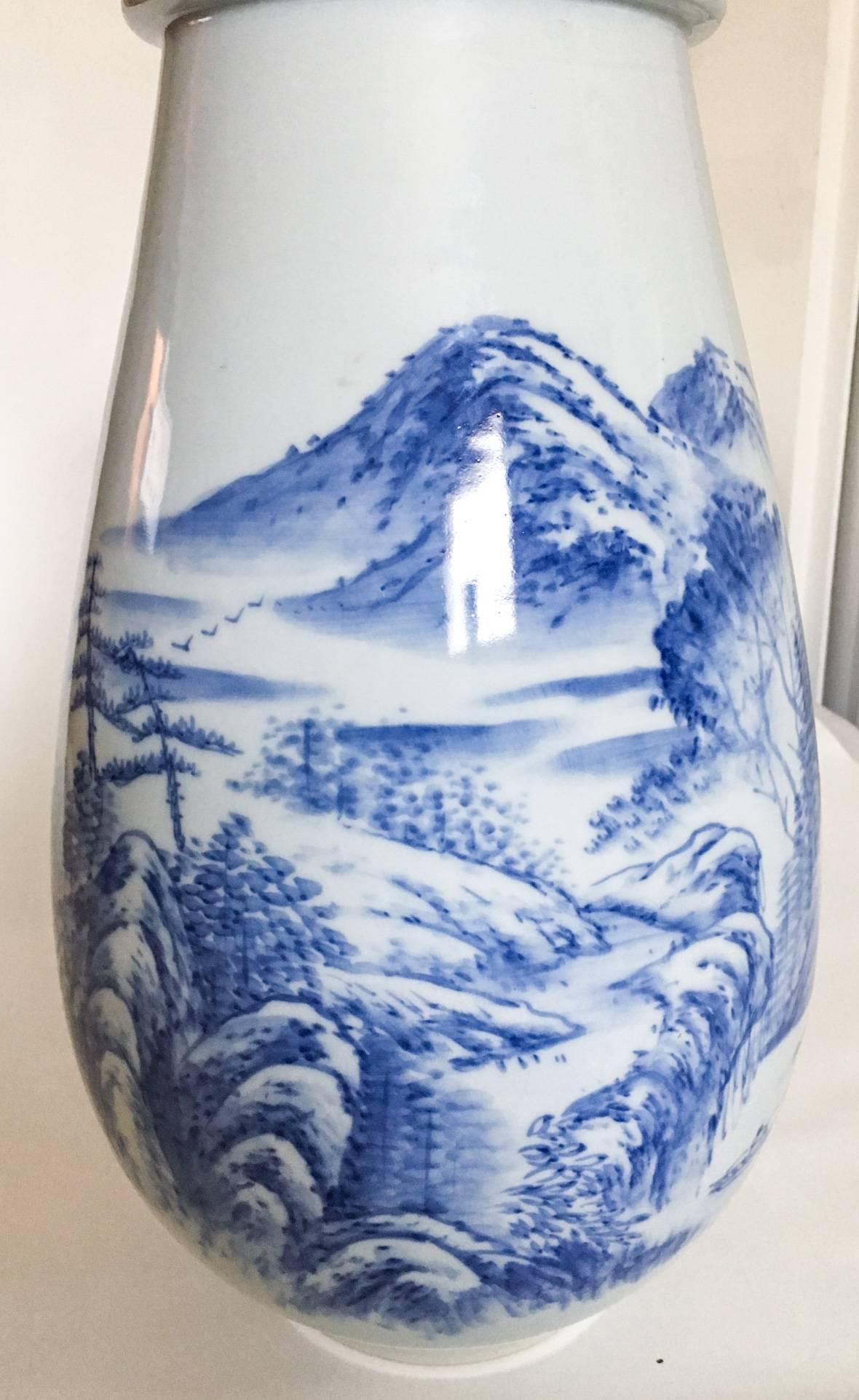 Offered is a substantial hand-thrown tall export ceramic vase, decorated with hand-painted cobalt blue motifs of mountains and trees along a river with a fisherman against a very pale robin's egg blue ground. Vase is marked with Chinese characters