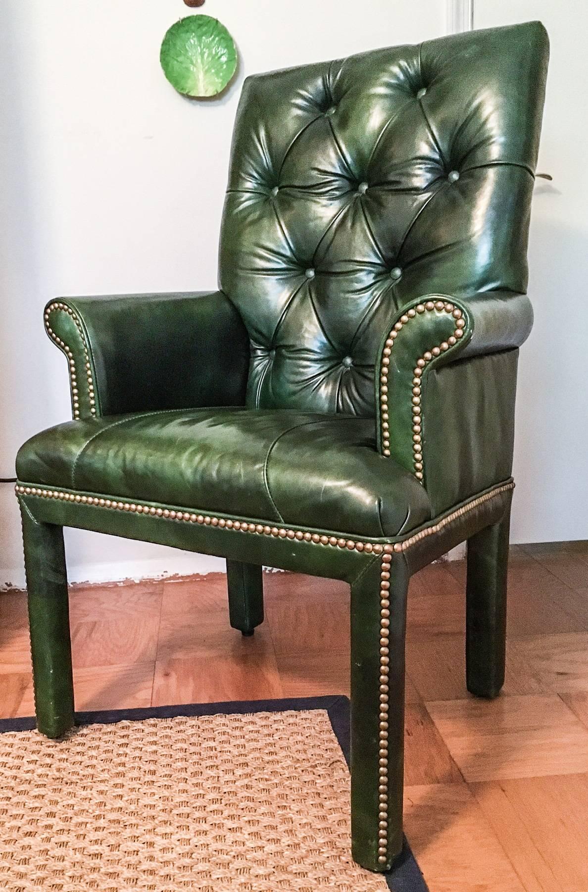 Fabulous tufted leather armchair by Michael Thomas Furniture, fully upholstered over a hardwood frame in a sensuous emerald green leather by Moore & Giles. Chair is finished with brass nail-head trim. A couple light scratches on the seat, which