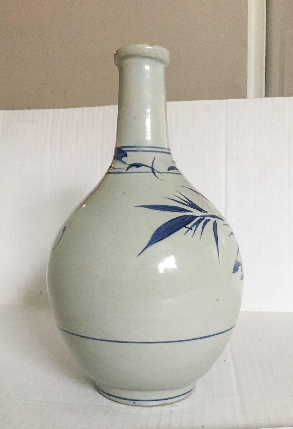 Wonderful antique hand-thrown pottery Japanese sake bottle, decorated with blue. Bottle leans slightly to the right when viewed from the front.