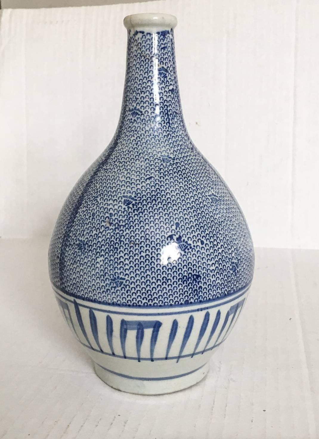 Elegant antique Japanese sake bottle decorated with an all-over blue webbing pattern and brushstroke detail around the base. Small hairline age crack at neck, shown in photograph #4. Unmarked.