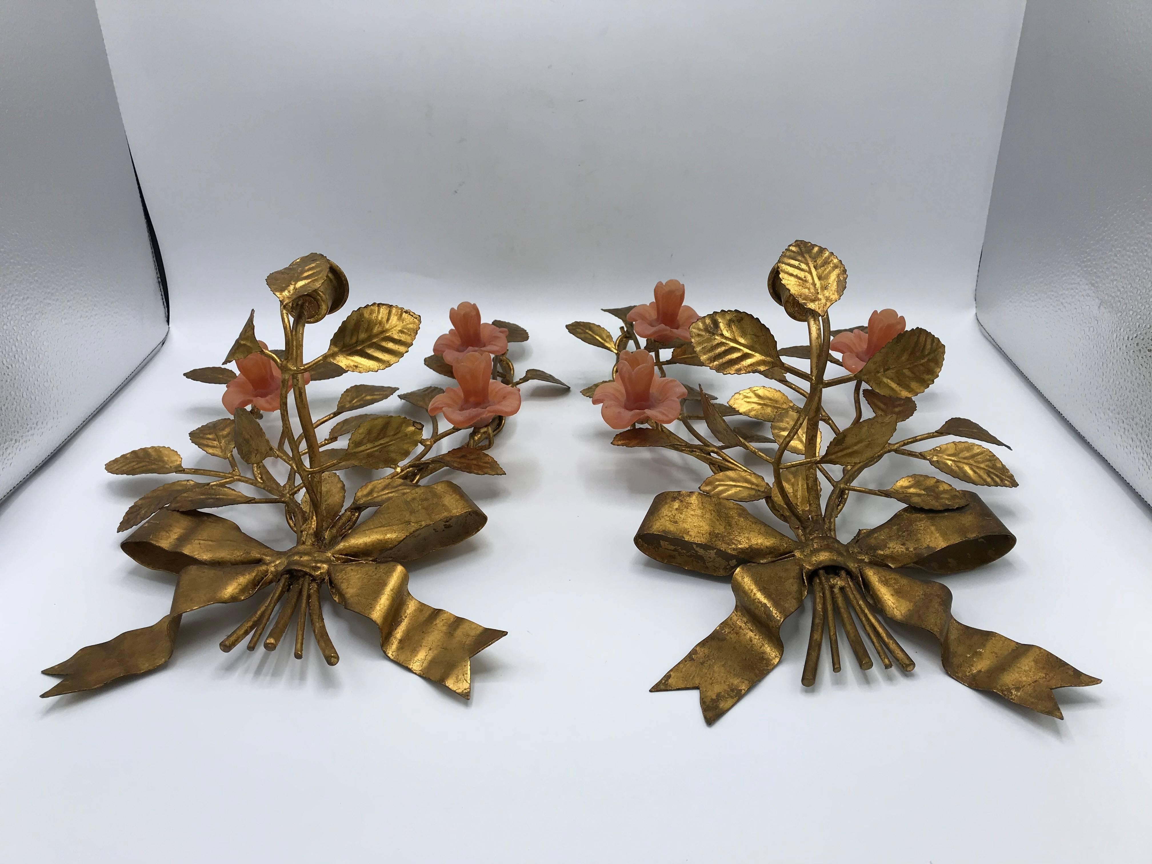 Offered is an exquisite, pair of 1960s Italian gilt wall sconces. Each are mirrored to one another, with three beautiful pink roses, gilt vines, and adorned with a knotted bow. The gilt frame is metal, roses are a matted resin. The candlestick arm