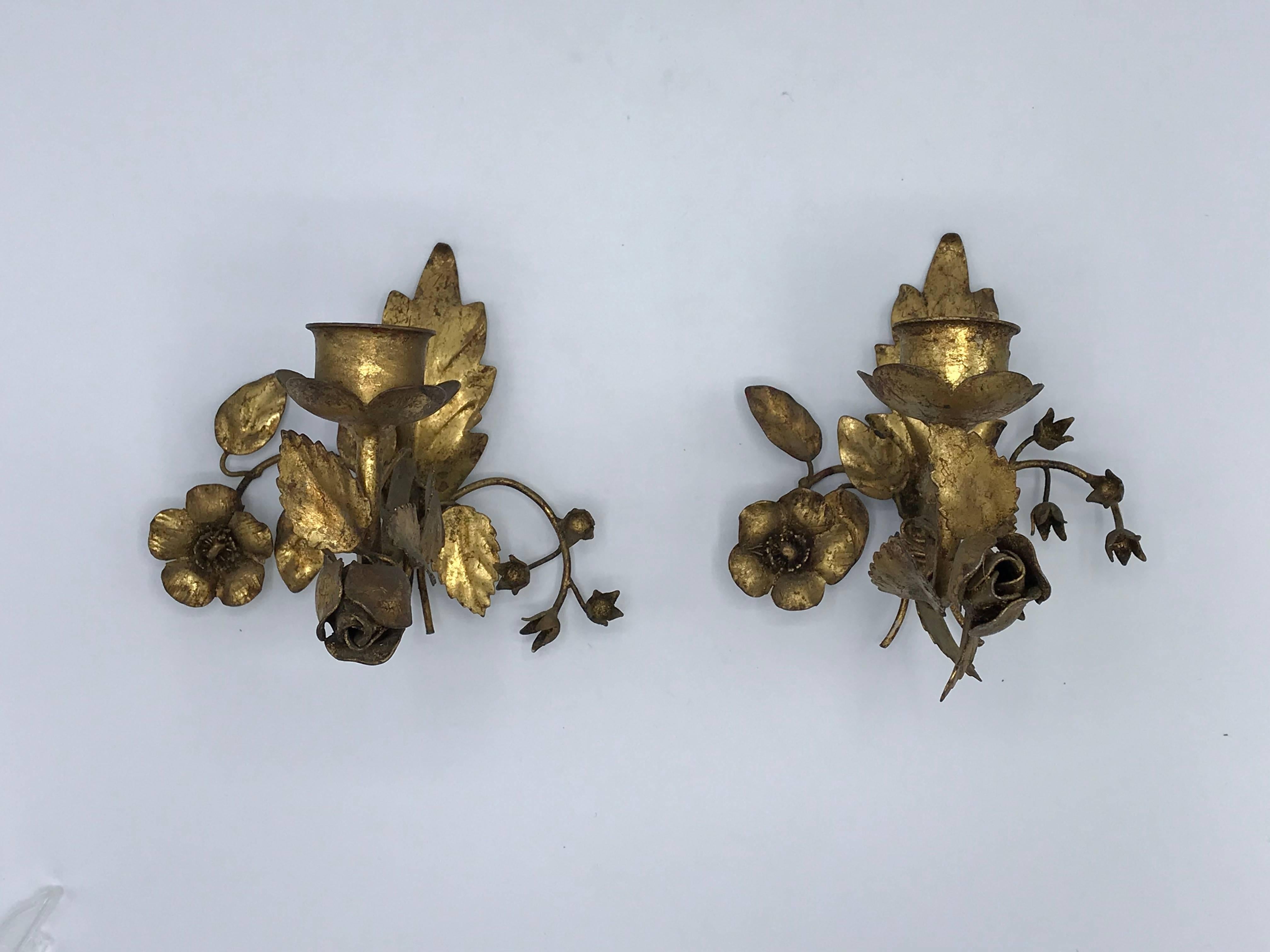 Offered is an exquisite, pair of 1960s Italian Florentine gilt wall sconces. The pair have a mirrored rose, vine, and floral sculpture motif. Hollowed inside, allowing for the pair to convert to electric sconces vs candlestick.