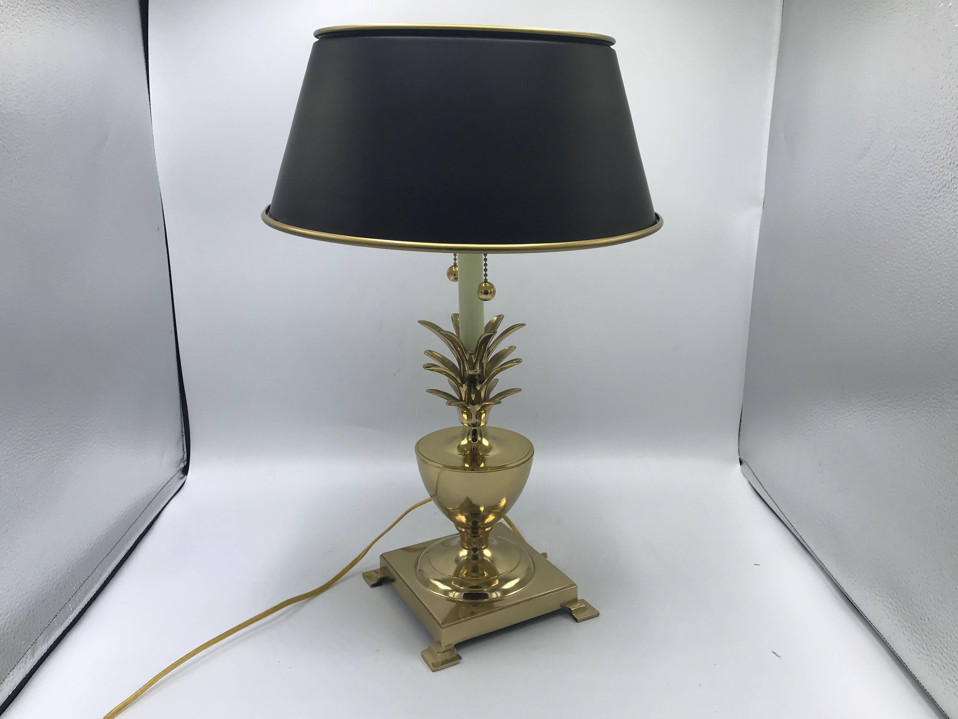 Offered is a stunning, 1970s brass pineapple lamp, in the style of Virginia Metalcrafters. The piece includes a black tole shade with gold piping and light-diffuser. Double socket, with chain pulls.