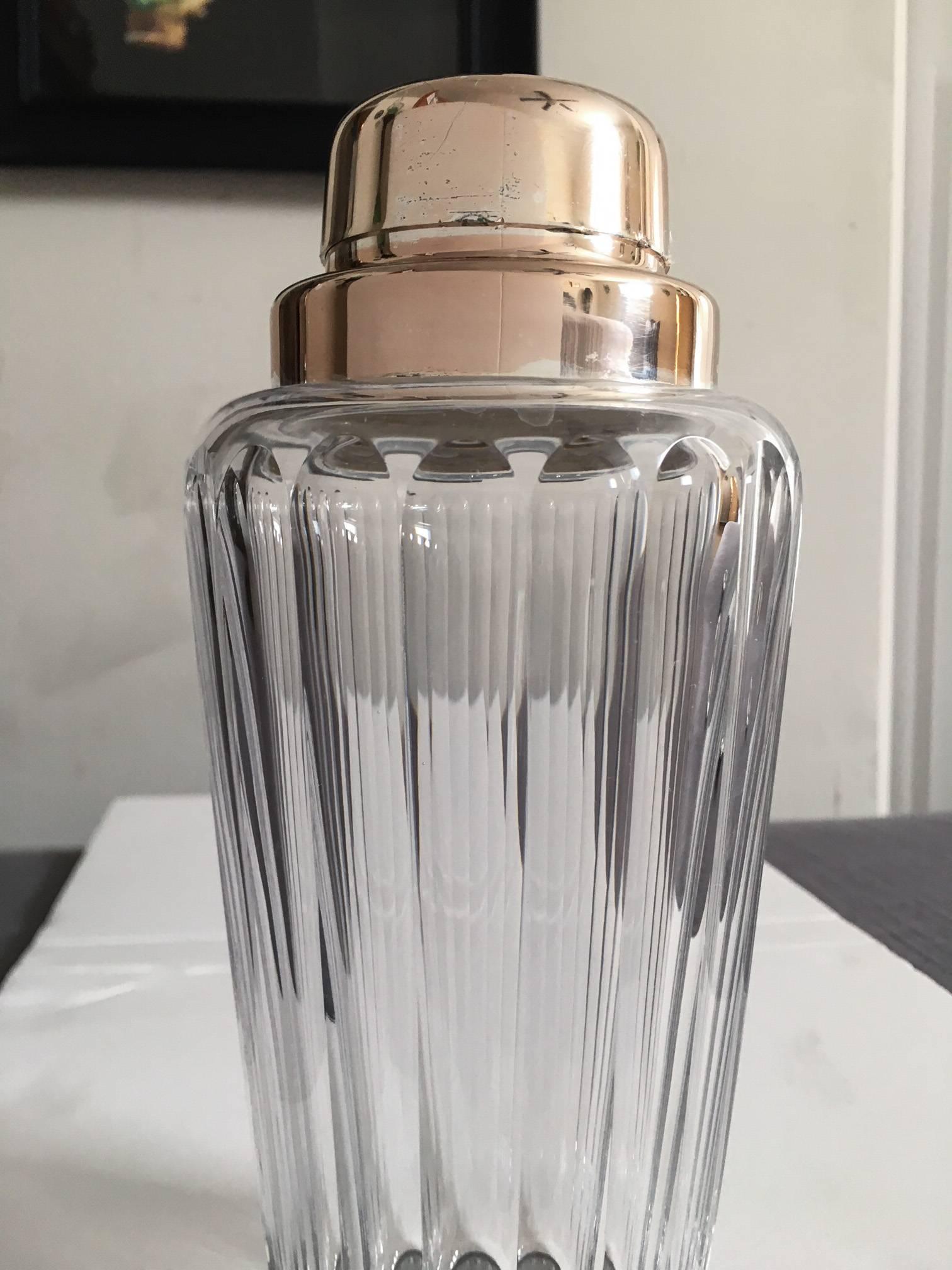 A heavy and elegant cut faceted crystal cocktail shaker with removable strainer, marked EPNS Germany on the underside of the lid. The glass body is in excellent condition with no chips. The lid and top of the shaker have aged to a silver-copper