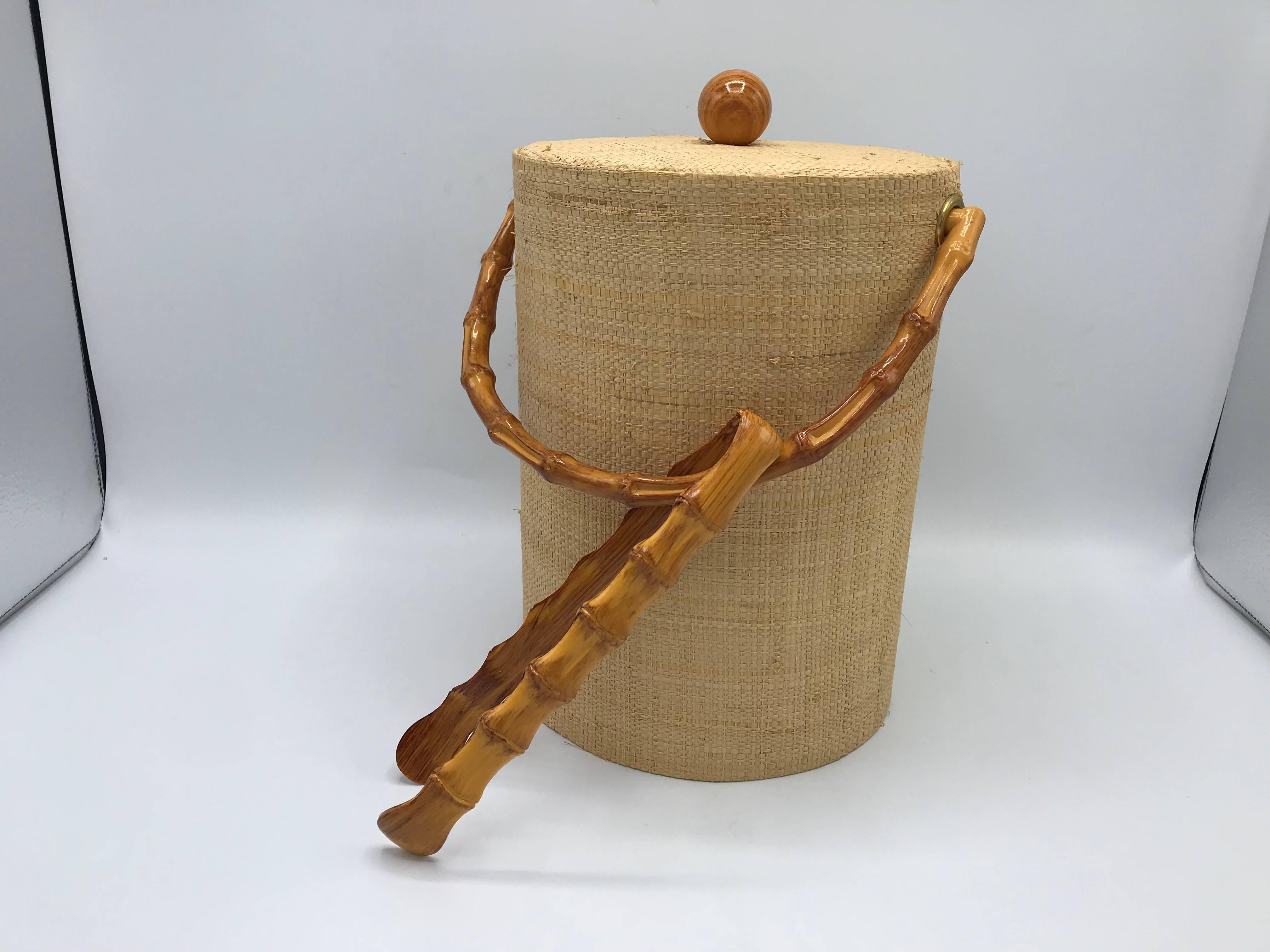 Offered is a fabulous, 1980s raffia wrapped ice bucket with a faux bamboo handle and matching faux bamboo tongs. The perfect addition to any Chinoiserie cocktail hour! Plastic liner. Excellent, never used condition.