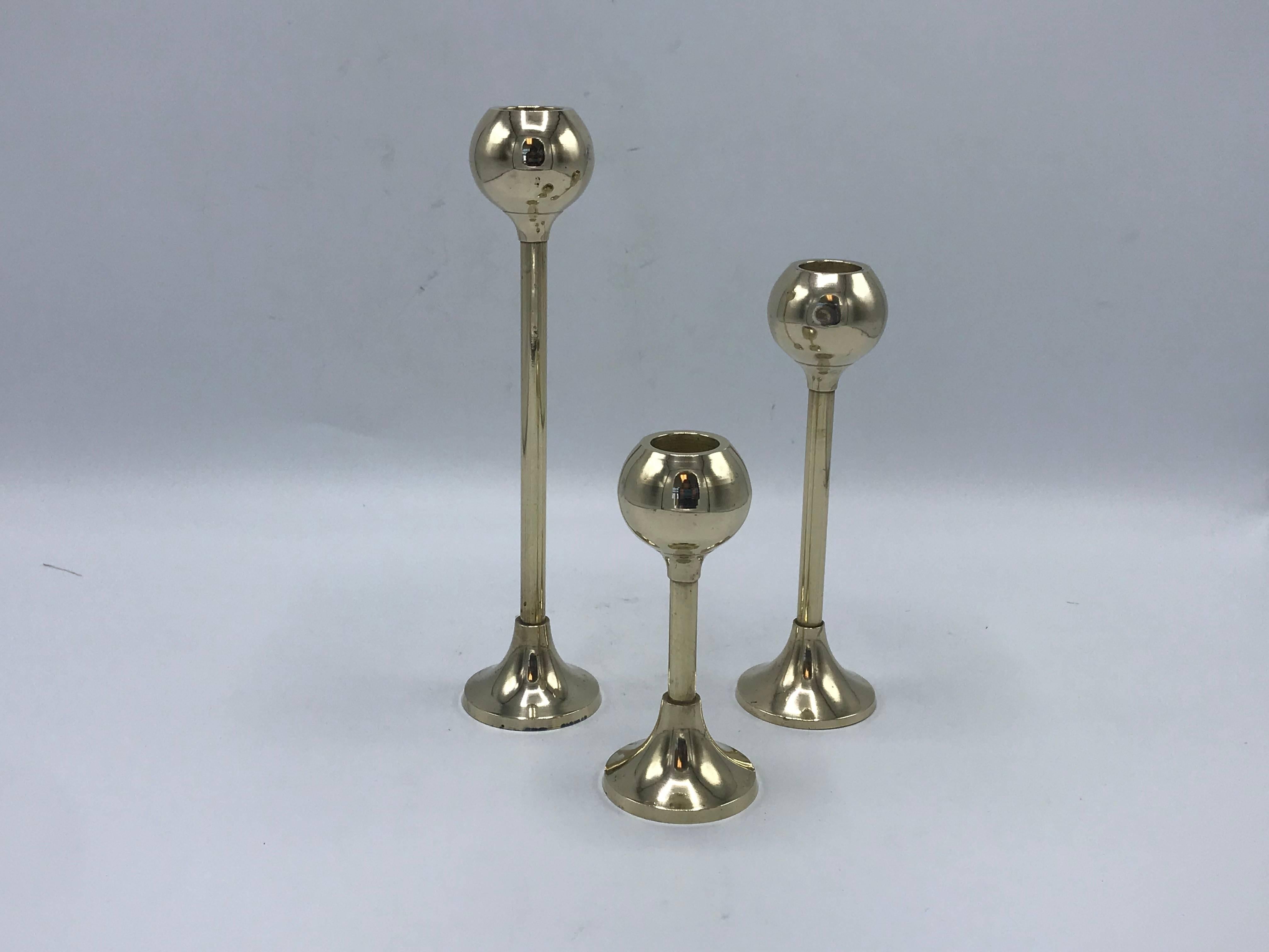 Listed is a gorgeous, set of three, 1970s Italian brass candlesticks with a modern floating orb. The set has been heavily polished, giving a mirrored brass effect. When not polished, the set turns a beautiful, warm brass patina. 

Large: 2
