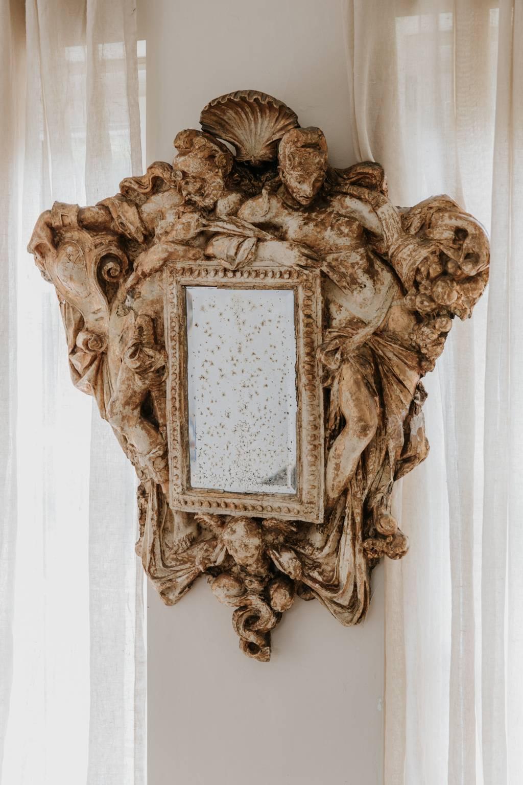 This is a very quirky 19th century mirror that once was part of the interior of a Parisian brothel, plaster with rests of old gilt, a male figure holding the inscription guerra and a female figure holding the inscription pace.