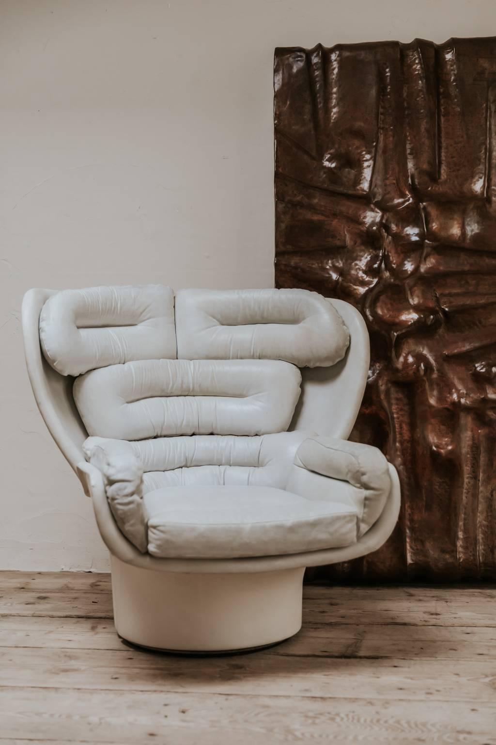 Der Loungesessel Elda wurde 1963 entworfen und besteht aus einer Fiberglasschale mit drehbarem Fuß, der Sitz ist mit weißem Leder gepolstert. Das von Joe Colombo entworfene Kultobjekt war für seine Entstehungszeit sehr futuristisch gestaltet.