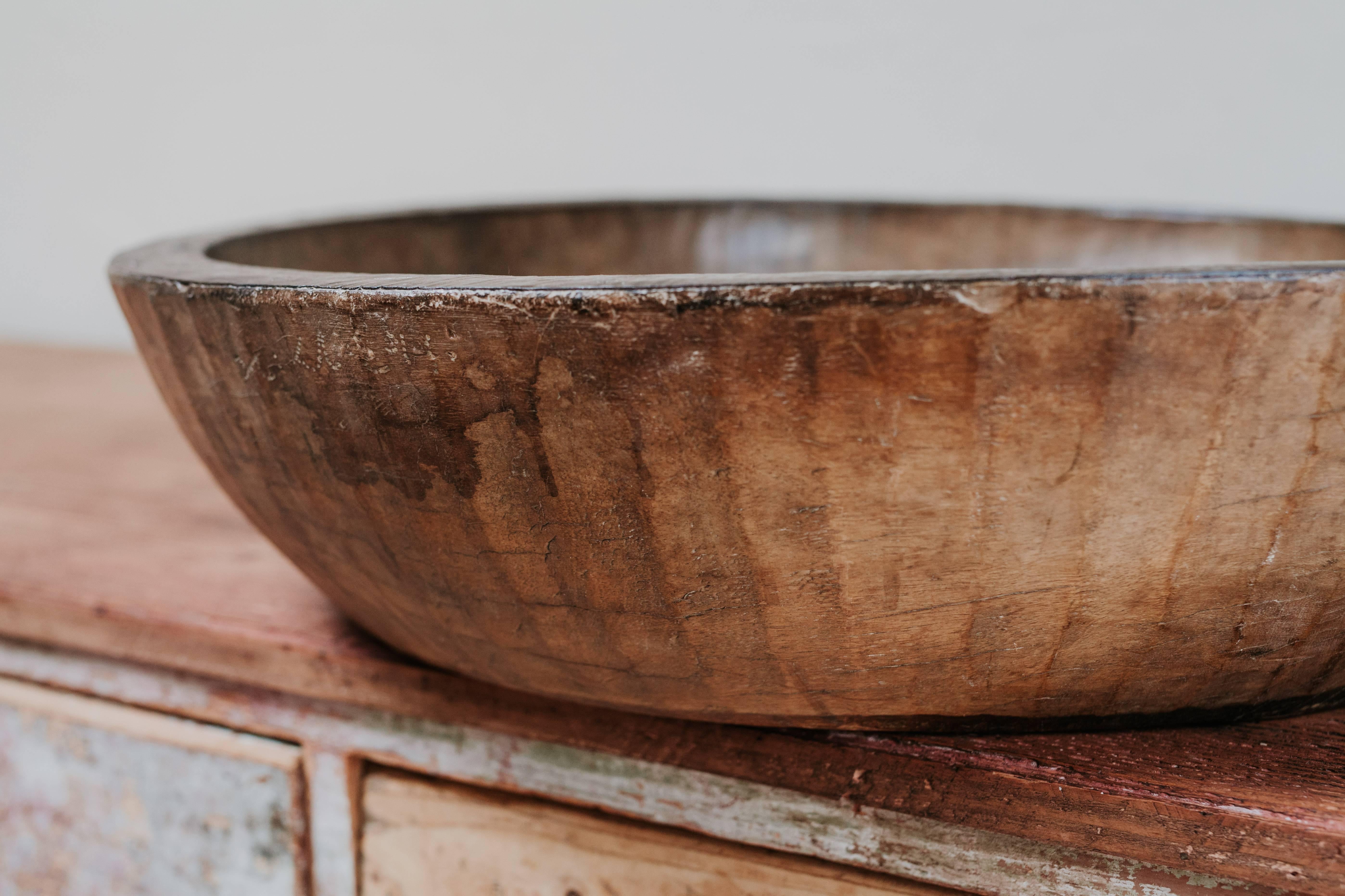 This extra large wooden bowl is carved from a single piece of wood, with original hand-wrought iron rim, an out of the ordinary object.