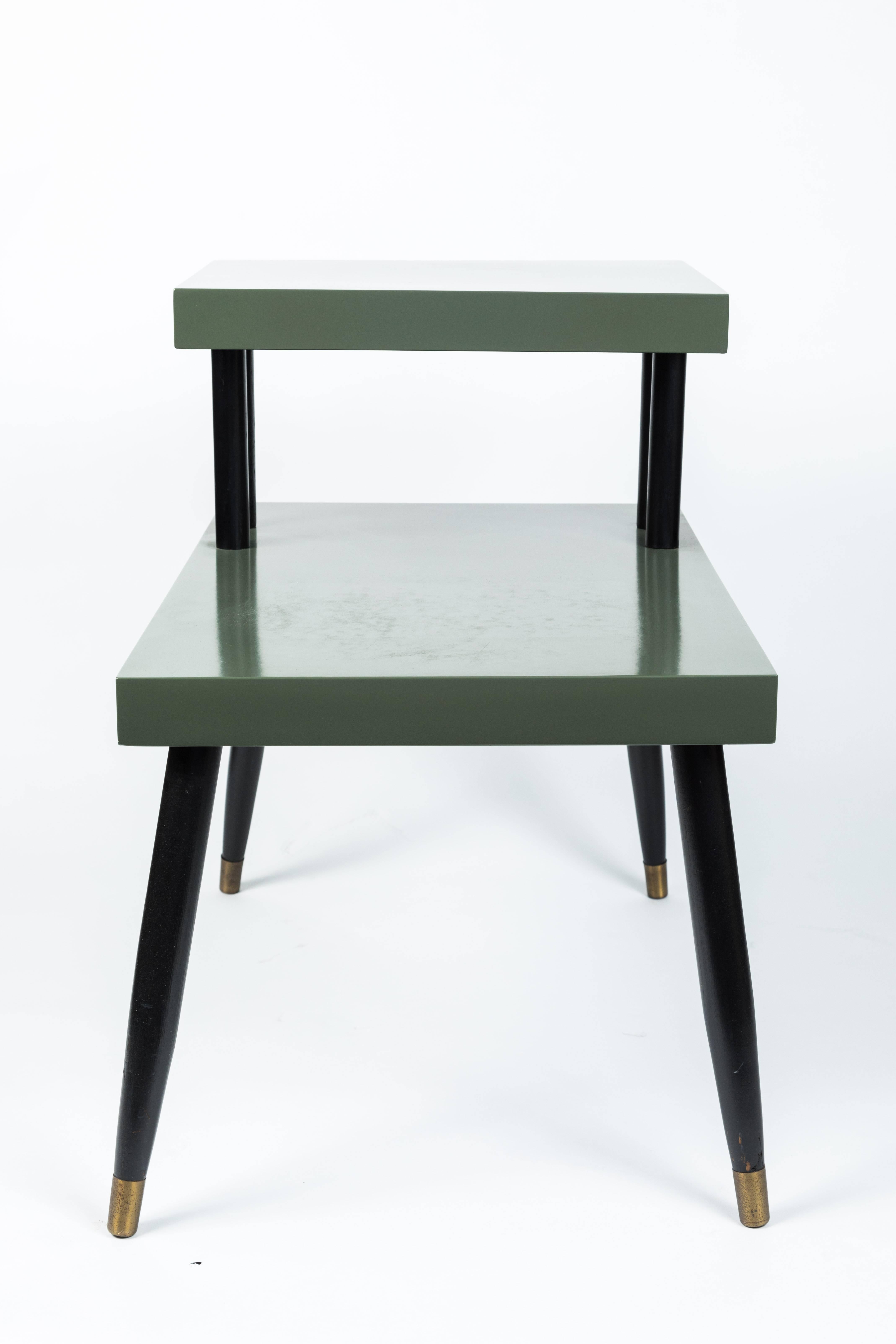 Mid-Century Modern two-tiered side table
American, 1950s
Sea foam green lacquer finish, with black legs and accents, brass capped feet.
Recently refinished.
 