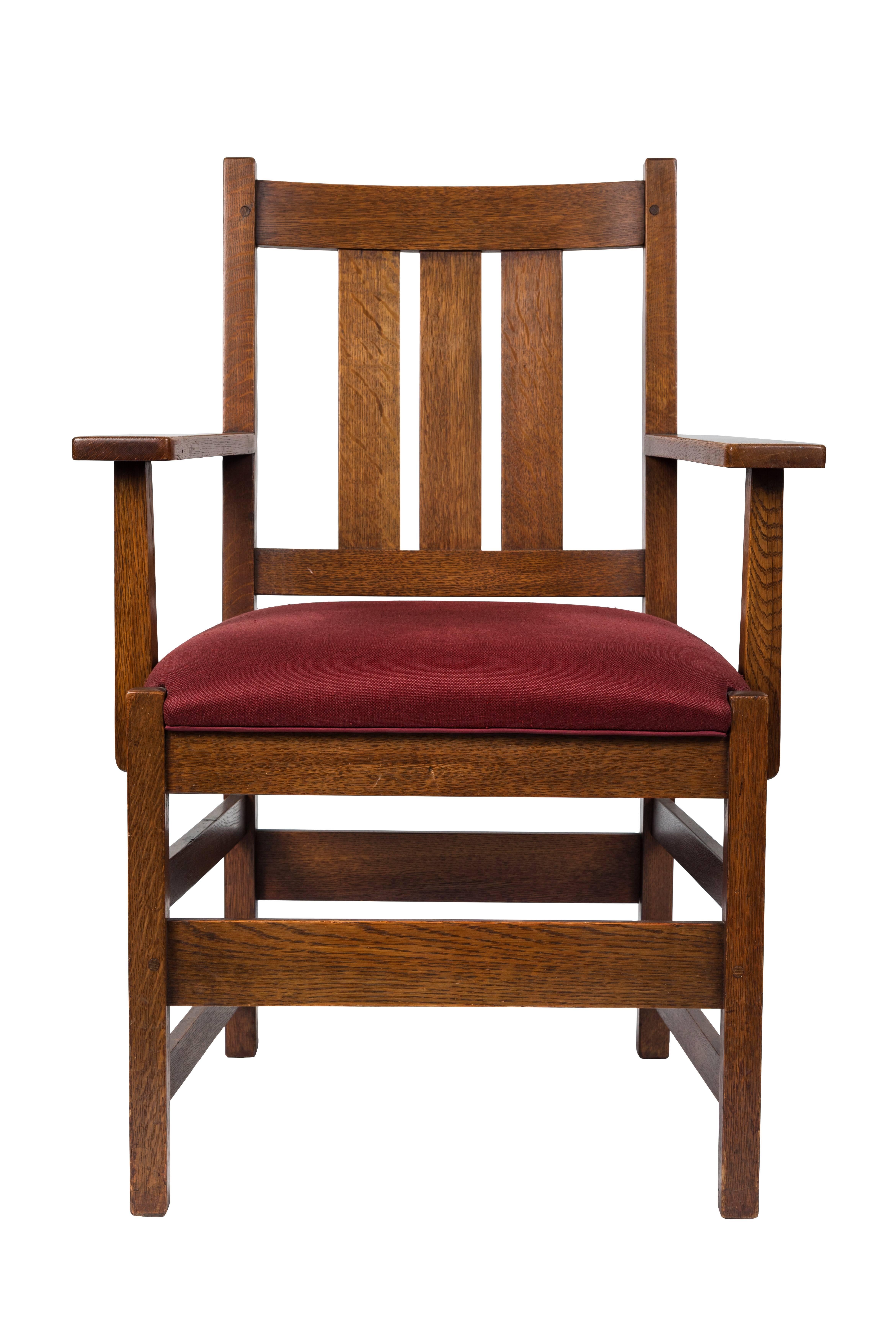 Two different but similar oak armchairs by L. & J.G. Stickley. Signed. Newly reupholstered in cranberry red linen, American, circa 1910. 

Measures: One chair is 18 in. D x 26.25 in. W x 37.5 in. H x 19.5 in. SH x 26.5 in. AH. 

Second chair is