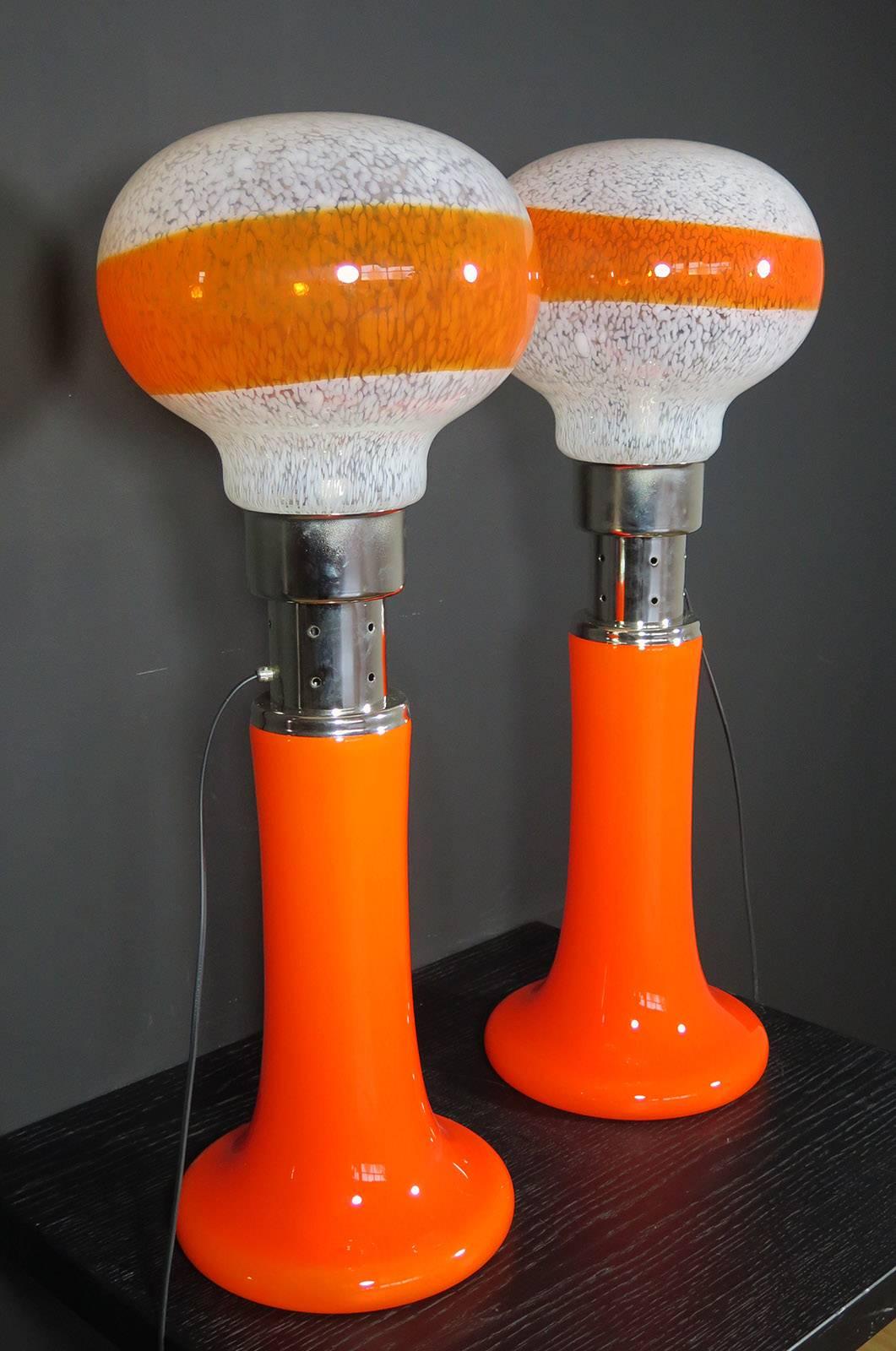 Pair of 1970 Spage Age Murano glass floor lamps by Mazzega, featuring a textured white bubbles on transparent blown glass top with orange band mounted on a orange glass base joined by a chromed steel frame and dual ignitions.
 