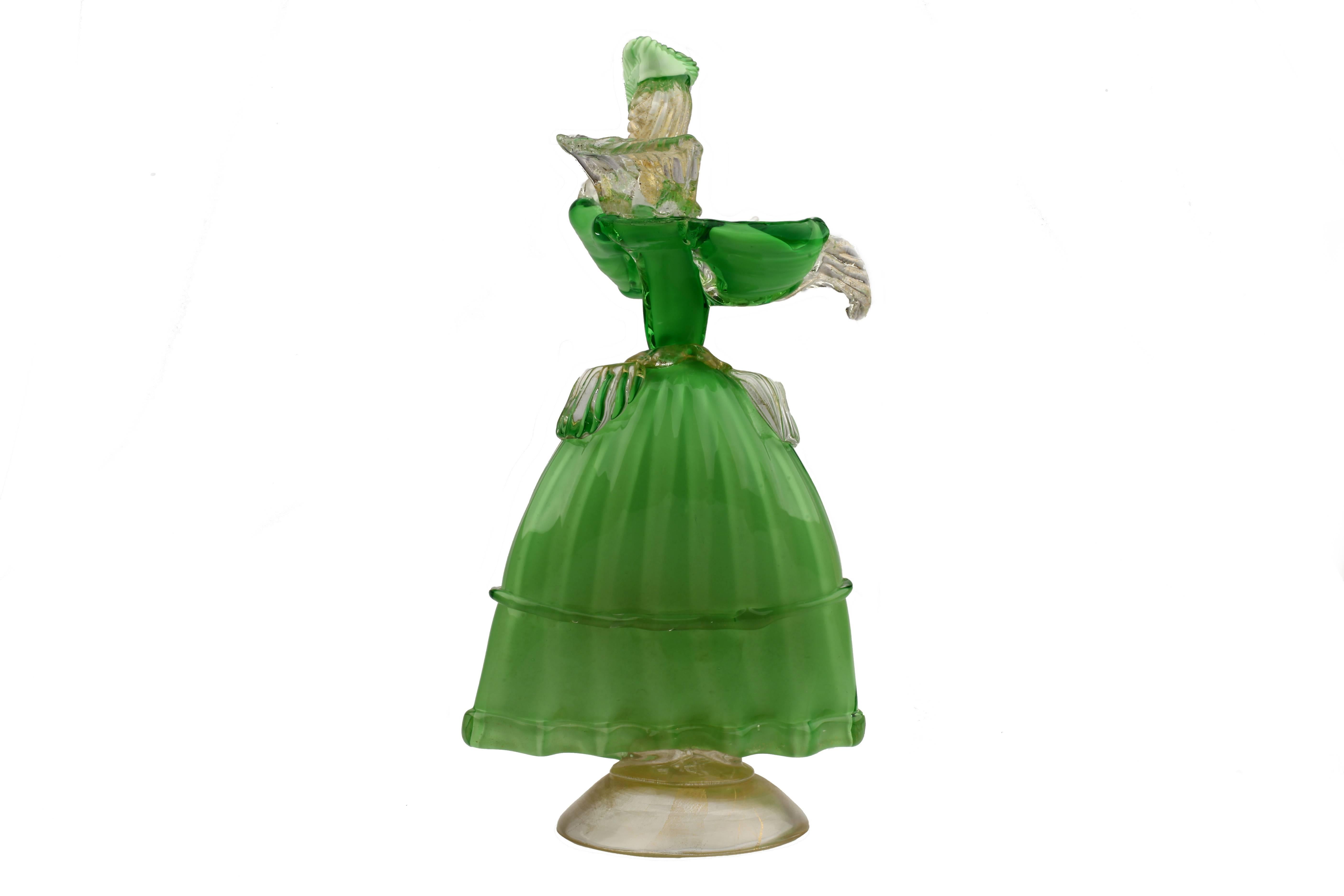 A stylish vintage Italian Formia Murano glass figurine of a lady in lavish and elaborate costume in green overlay glass on a white glass ground with white glass arms and head with clear glass frills with gold flecks and domed ribbed base with