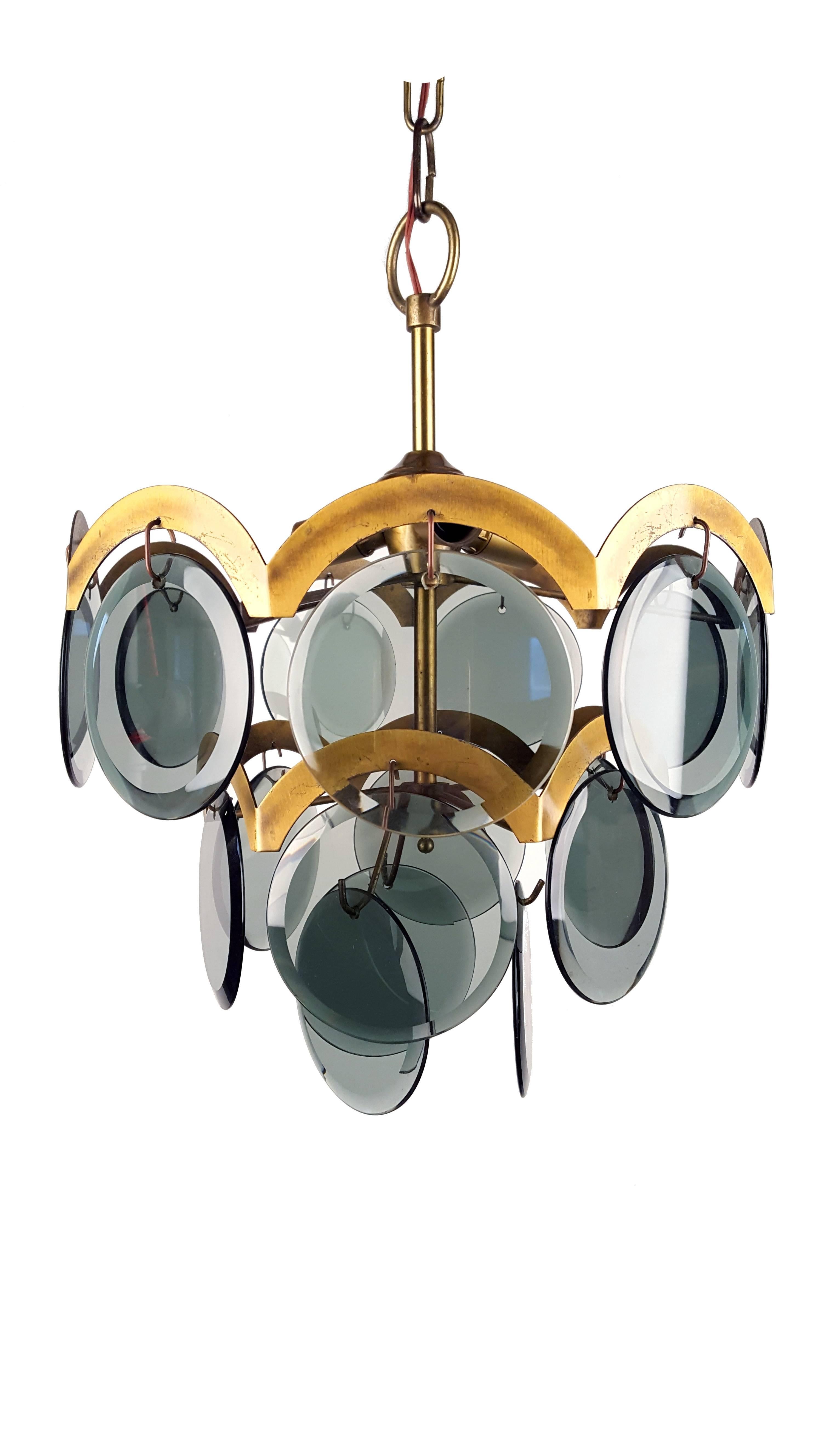Gino Vistosi Italian Mid-Century Modern smoked blue glass beveled disc and brass chandelier. Glass discs disposed in three rows. Three sockets for bulbs.

Measures: Height 35 cm (without chain)/13.8 inch.
Diameter 35 cm / 13.8 inch.
Diameter