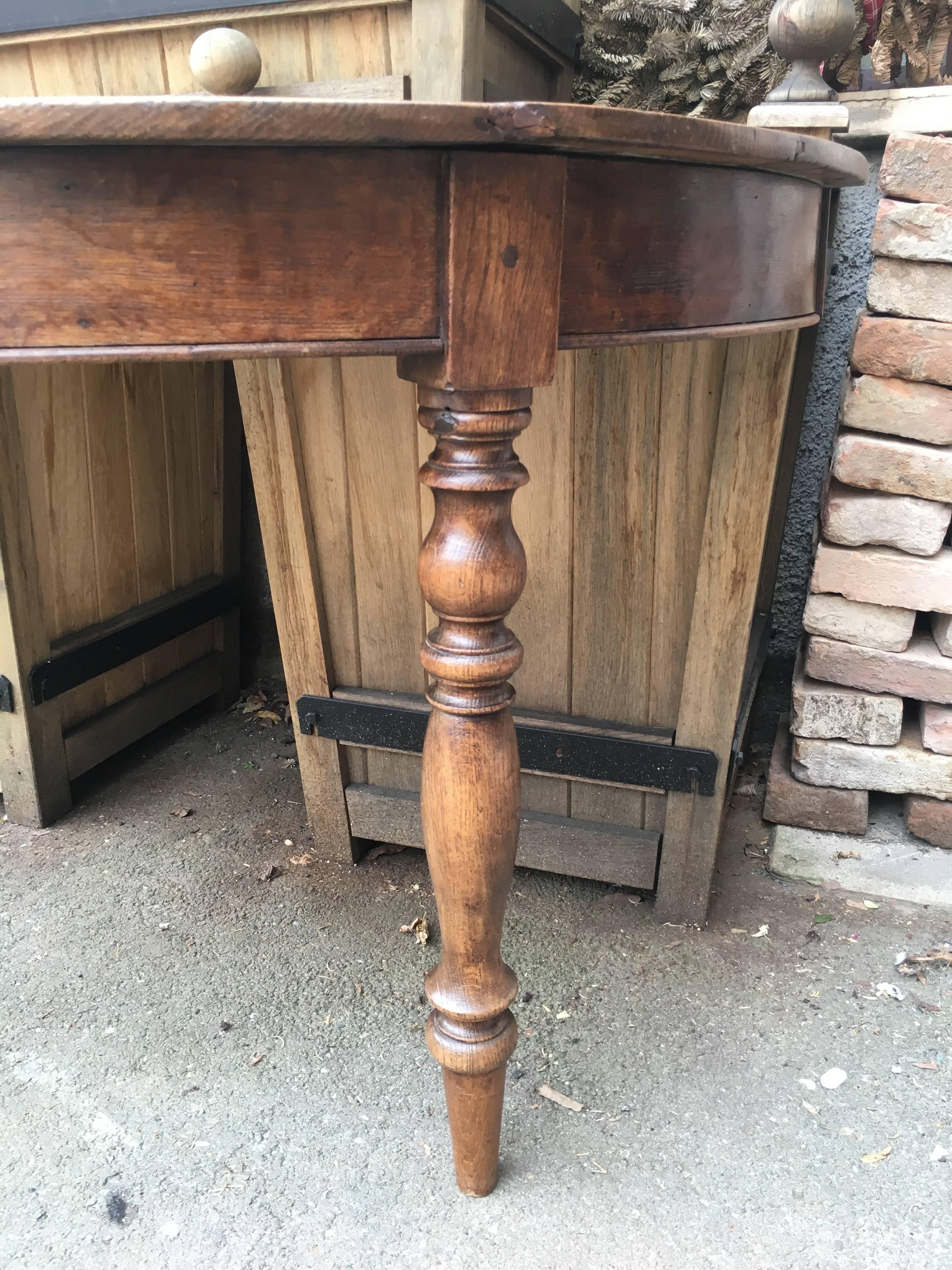 Half-circle console table with two turned legs.