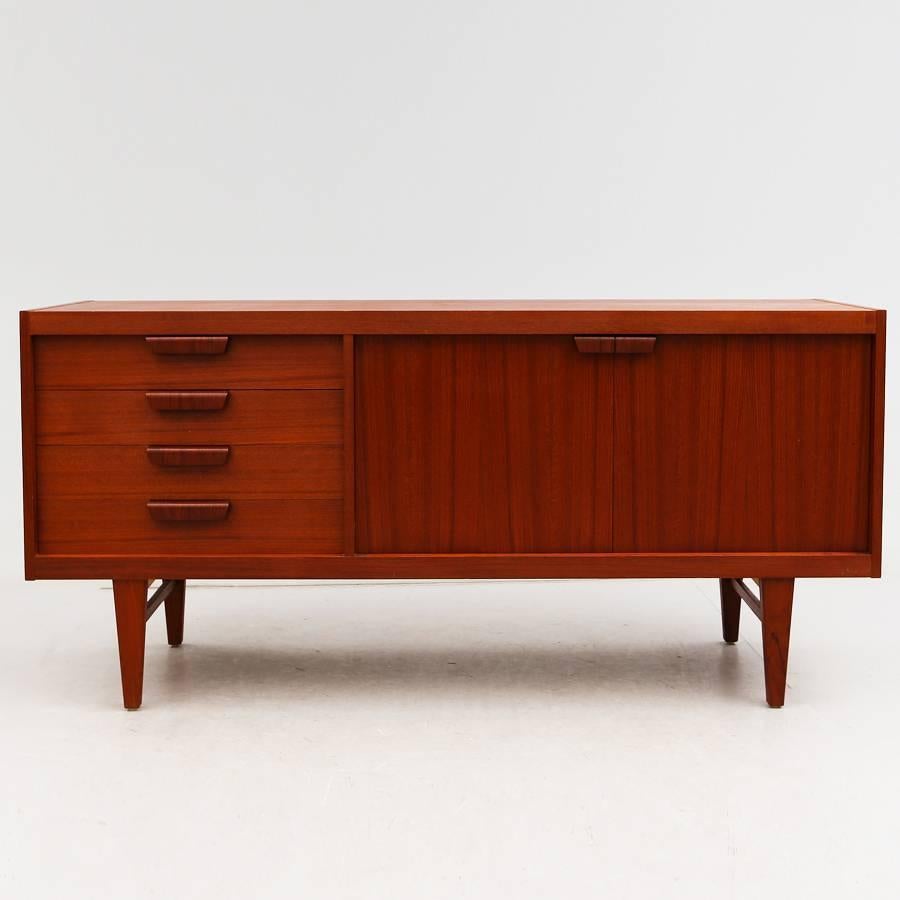 Sideboard in teak with two doors and drawers in excellent condition. The sideboard is framed by a large teak band.
