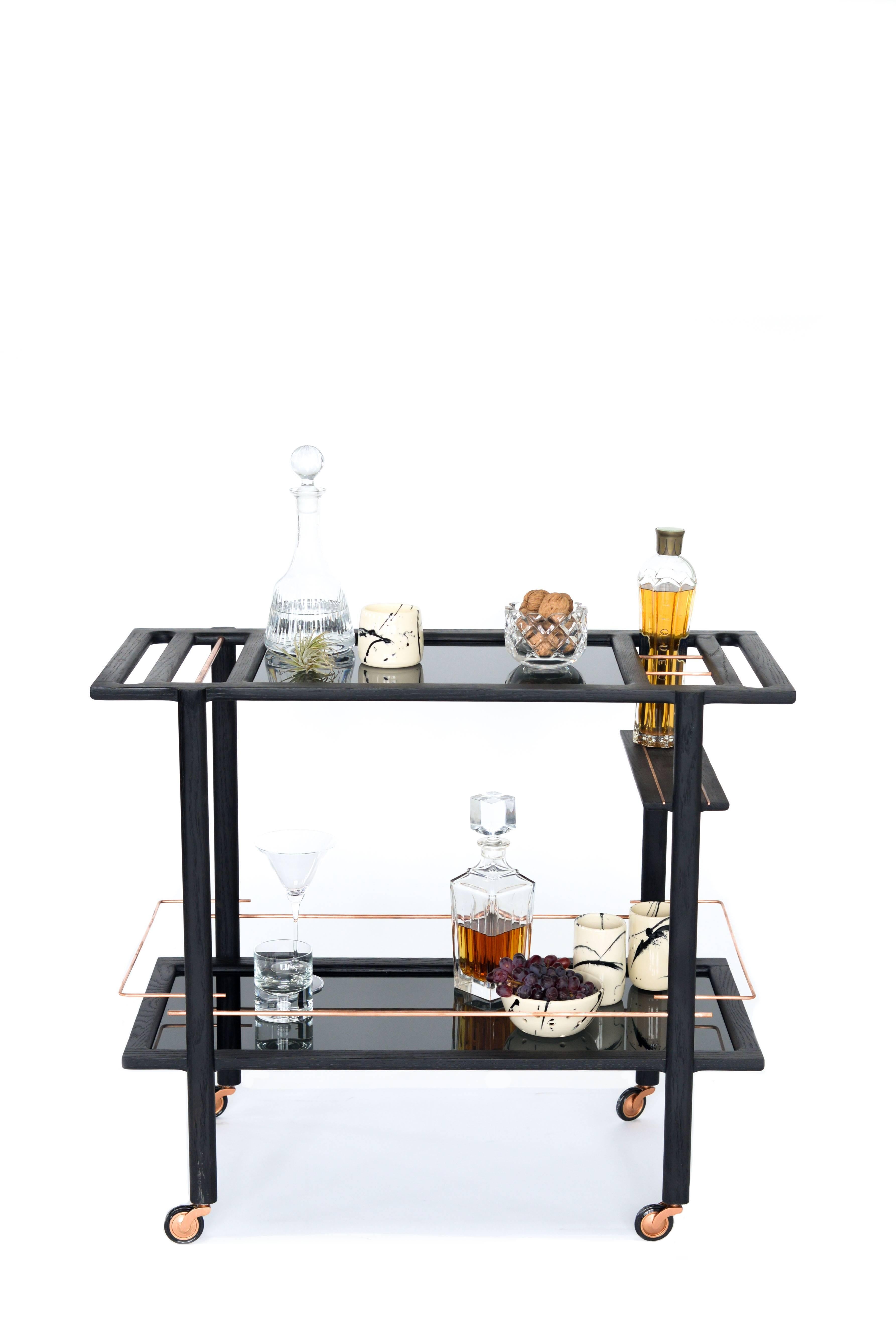 Solid wood constructed barcart with hand-cut joinery, tempered glass panels, and fine metal accents. Handmade in Los Angeles, California.  

Shown in ebonized oak, copper with smoked glass. 

Please inquire for custom wood, metal and glass options. 