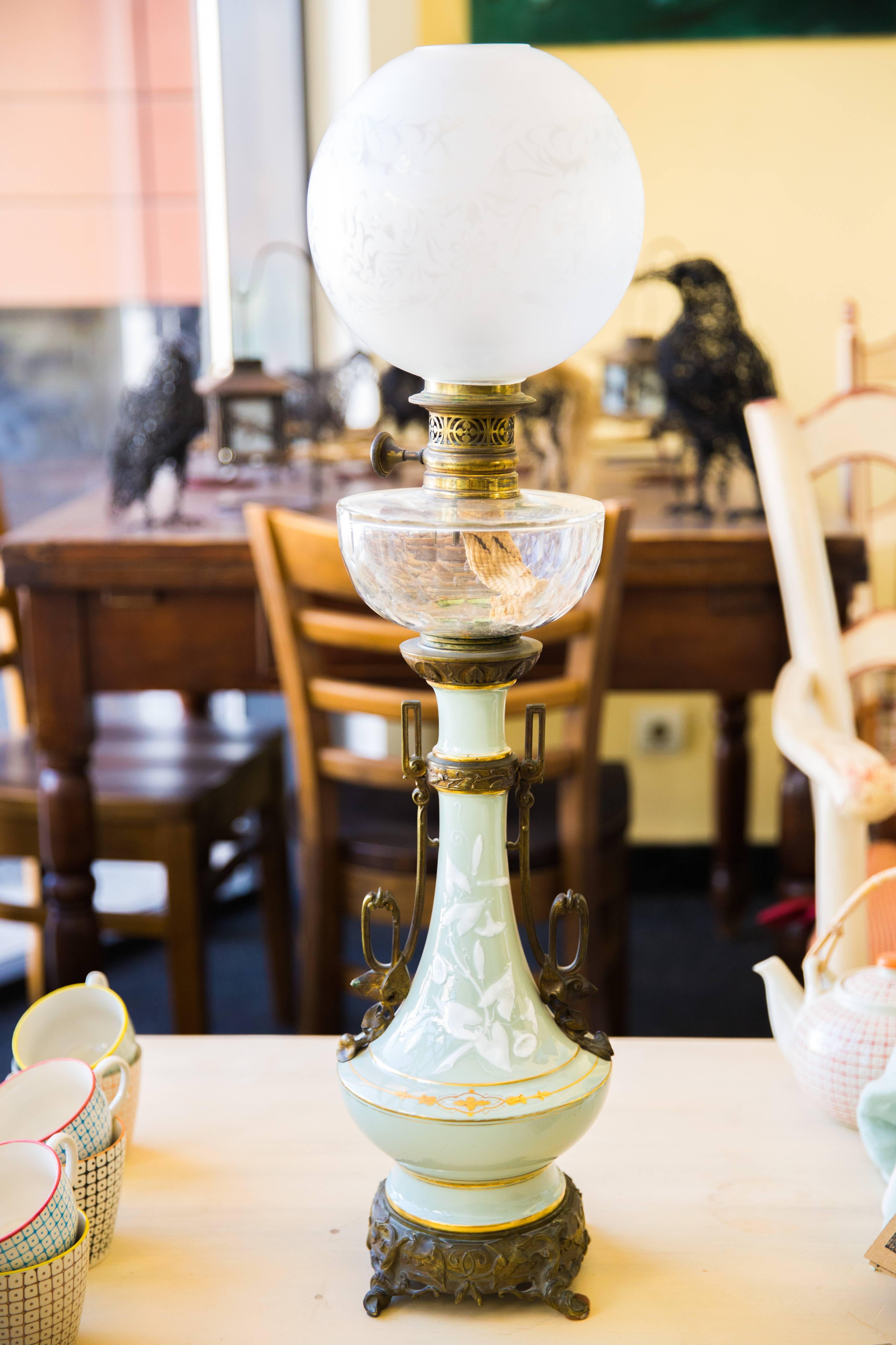 Exceptionnelle lampe en porcelaine avec brûleur à huile d'origine, raccord en bronze et boule en verre opalin gravé. Motifs floraux peints à la main sur un fond bleu pâle. Lampe très élégante en très bon état,
France, datant d'environ 1900.