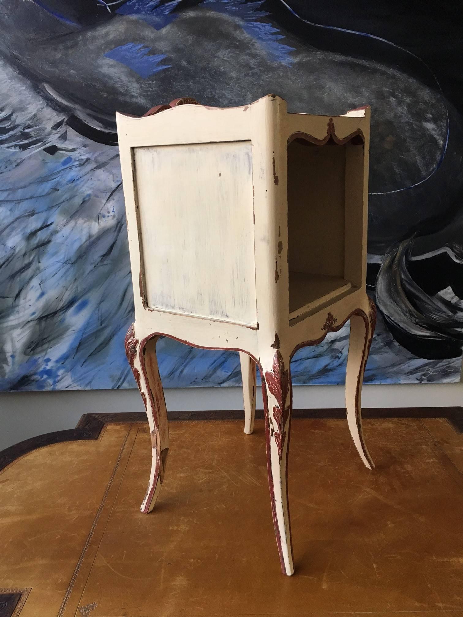 Two elegant solid wood nightstands or side tables, Louis XV style painted in light beige with coral accents. Made from carved wood, circa 1870.