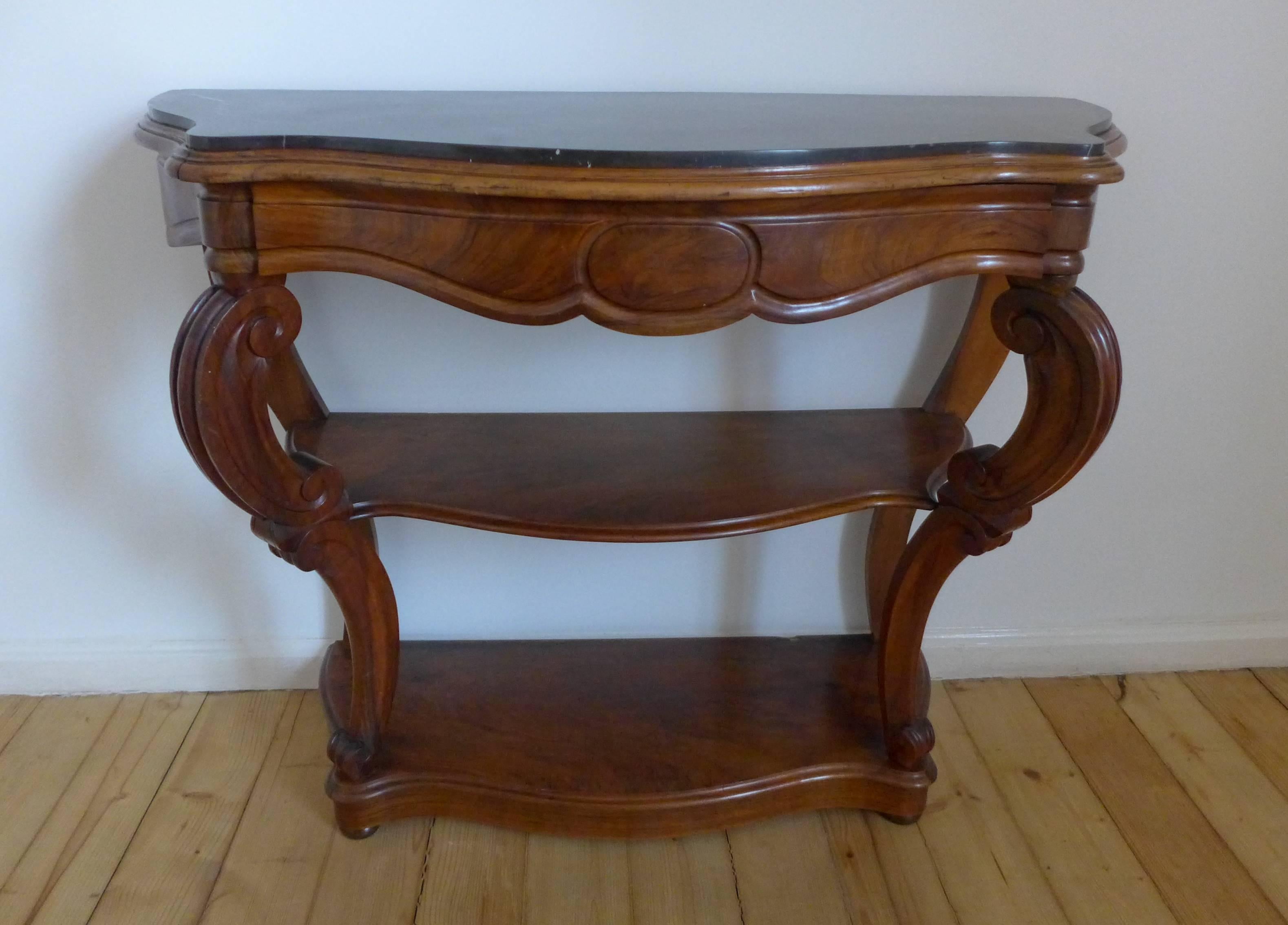 A beautiful 19th century antique French walnut console. This piece works double duty as a console with two tiers of shelving flanked by two supports that gracefully curve. There is a wide drawer and a dark green marble top in a very elegant shape. A