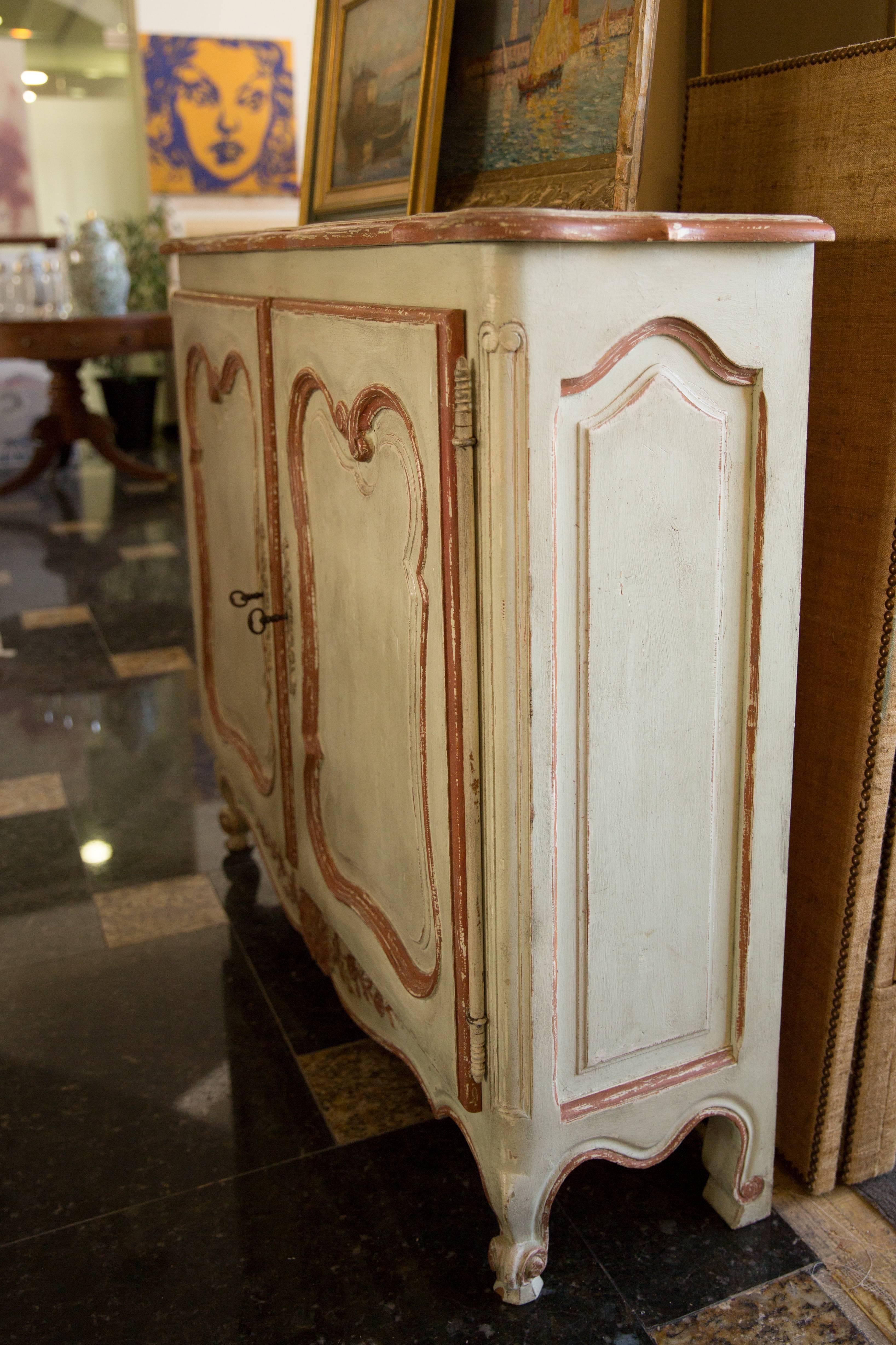 Beautiful Louis XV style hand-painted cabinet with two doors and charming design. Made of solid wood and perfectly painted in a soft light green with an antique distressed coral finish. This gives the look of a beautiful aged finish. Piece rests on
