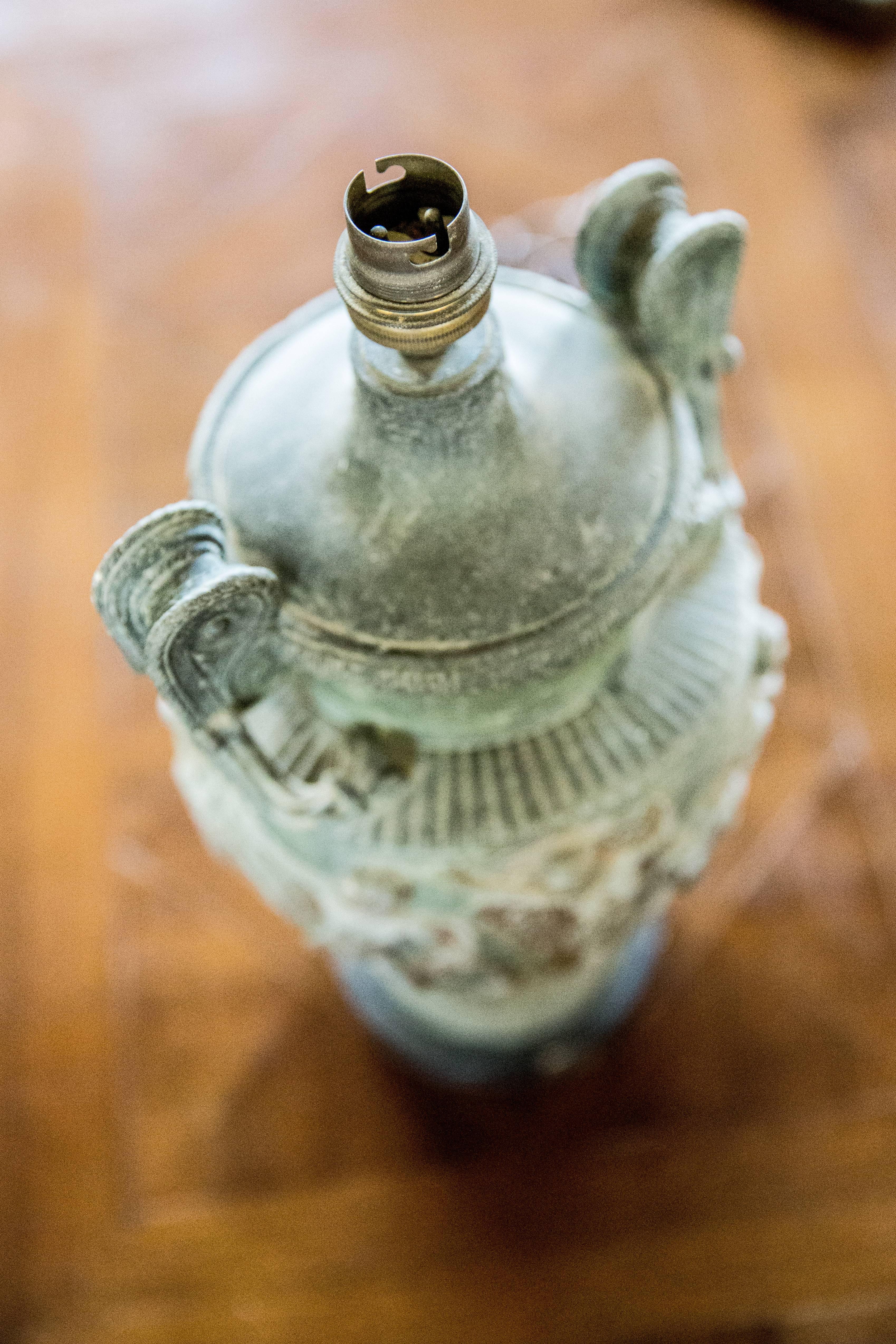 urne en métal du 19ème siècle avec des figures mythologiques sur un socle en pierre convertie en lampe avec une ampoule.
France, vers 1890.