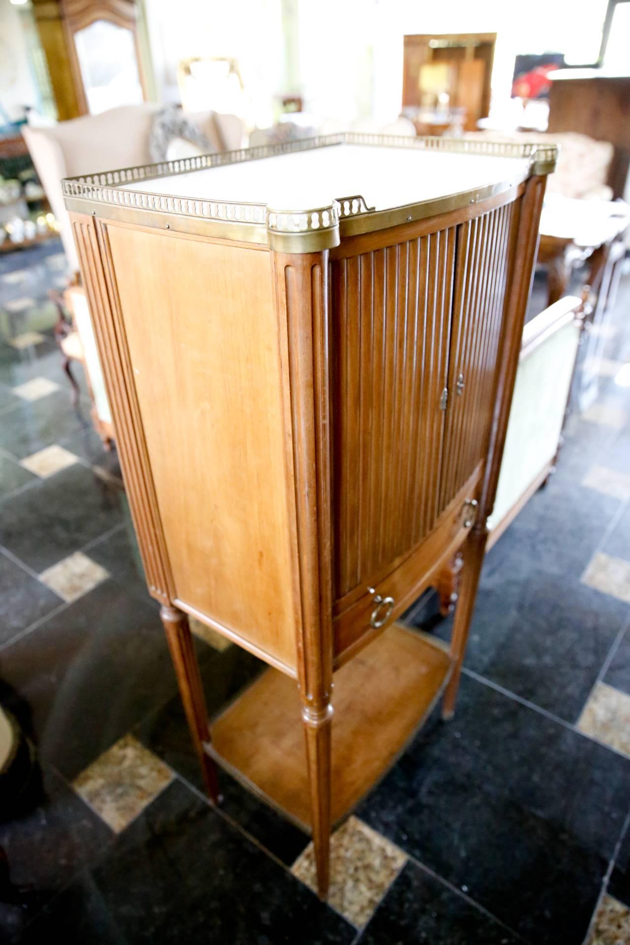 A very fine quality Louis XVI style French cabinet in solid wood with a lustrous French polish finish, hand-carved fluting, white marble top with brass gallery. Two doors and a drawer front the cabinet and there is a bottom shelf with brass gallery