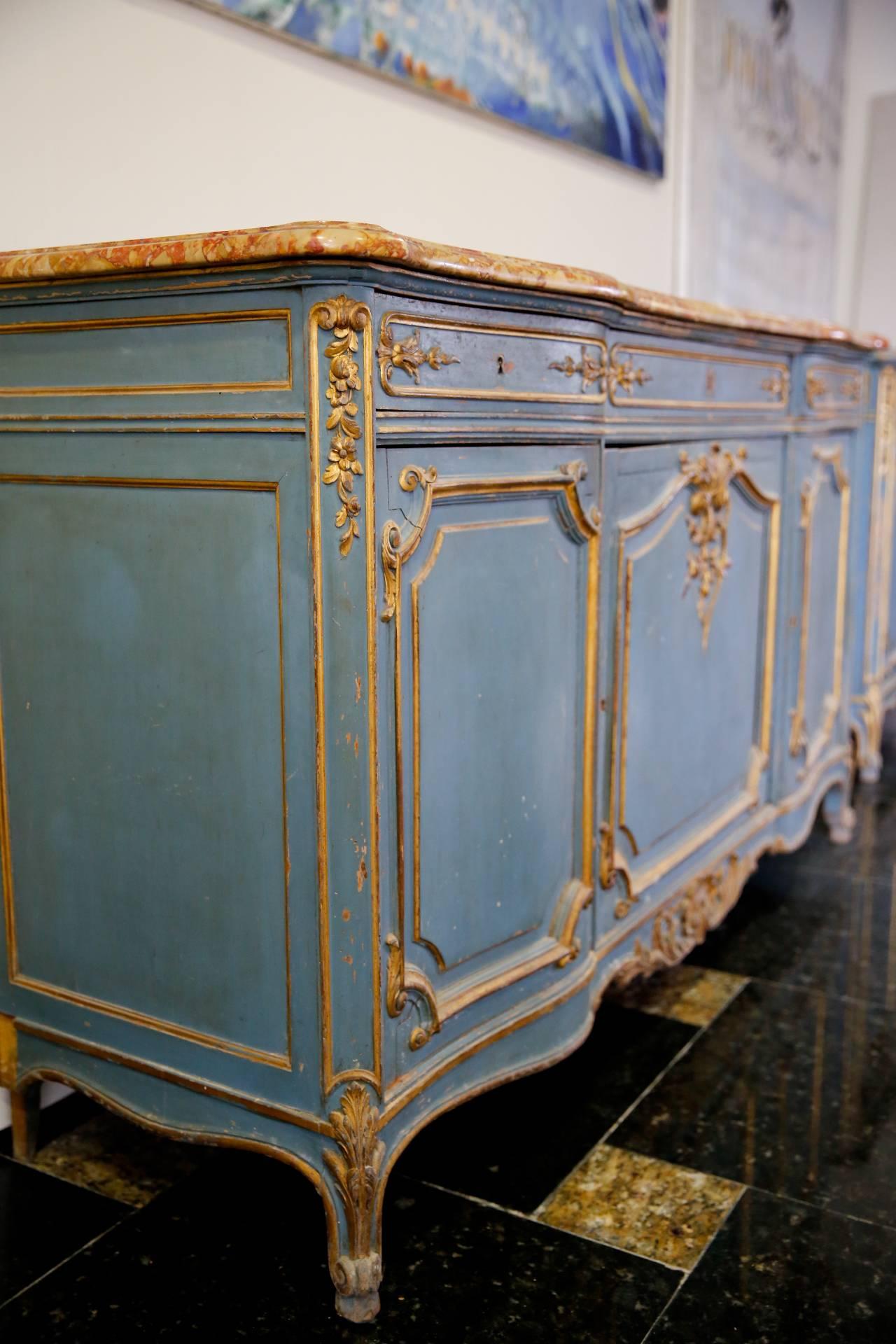 A very charming later 19th century, French Provençal enfilade buffet. It is done in painted wood in gold and light blue with a beautifully shaped marble top in terracotta and yellow. Three molded door panels and three drawers, all with wonderful