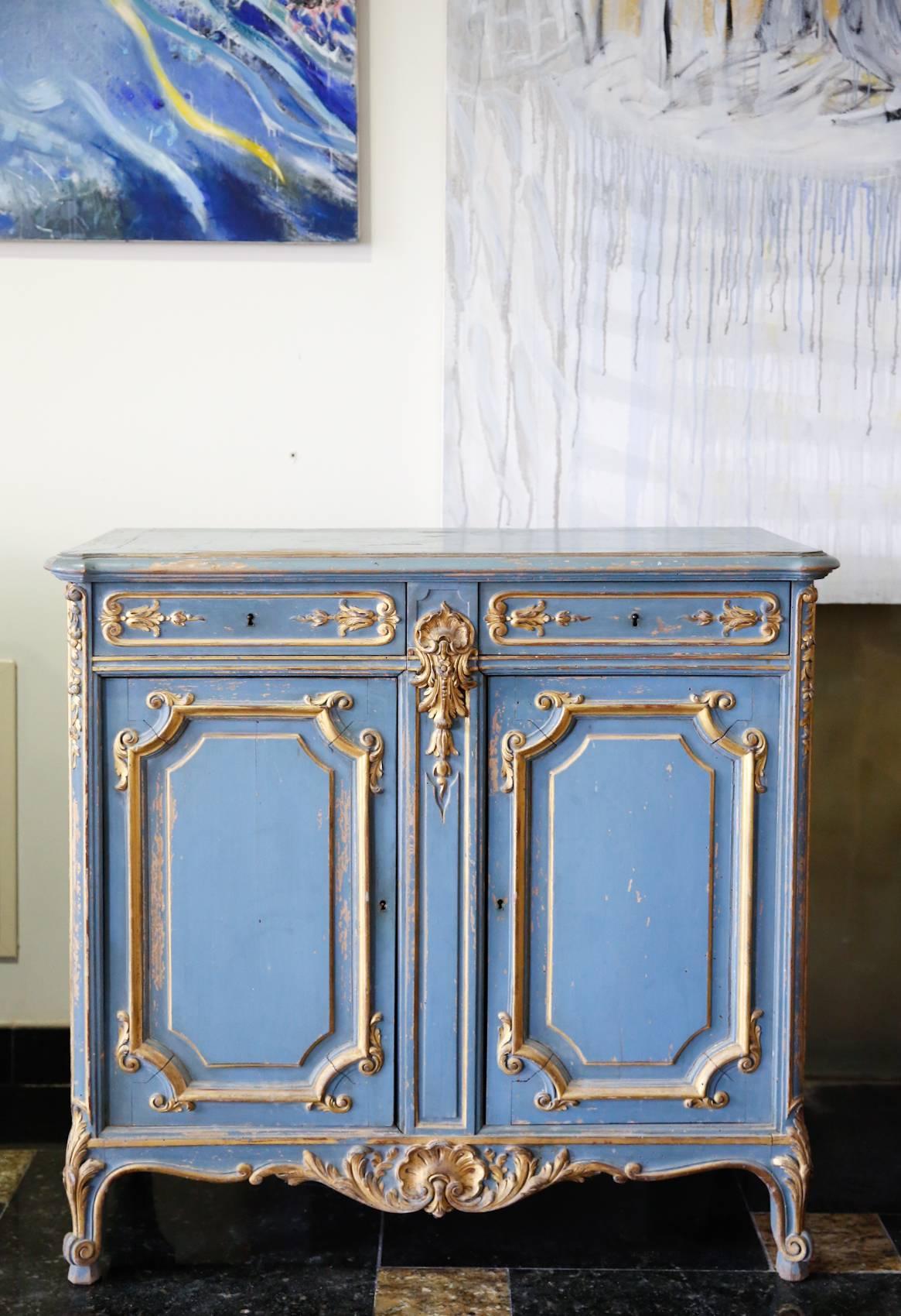19th century beautiful Louis XV style hand-painted cabinet with two doors and two drawers and charming design. Made of solid wood and perfectly painted in a light blue with an antique gold accents. This gives the look of a beautiful aged finish.