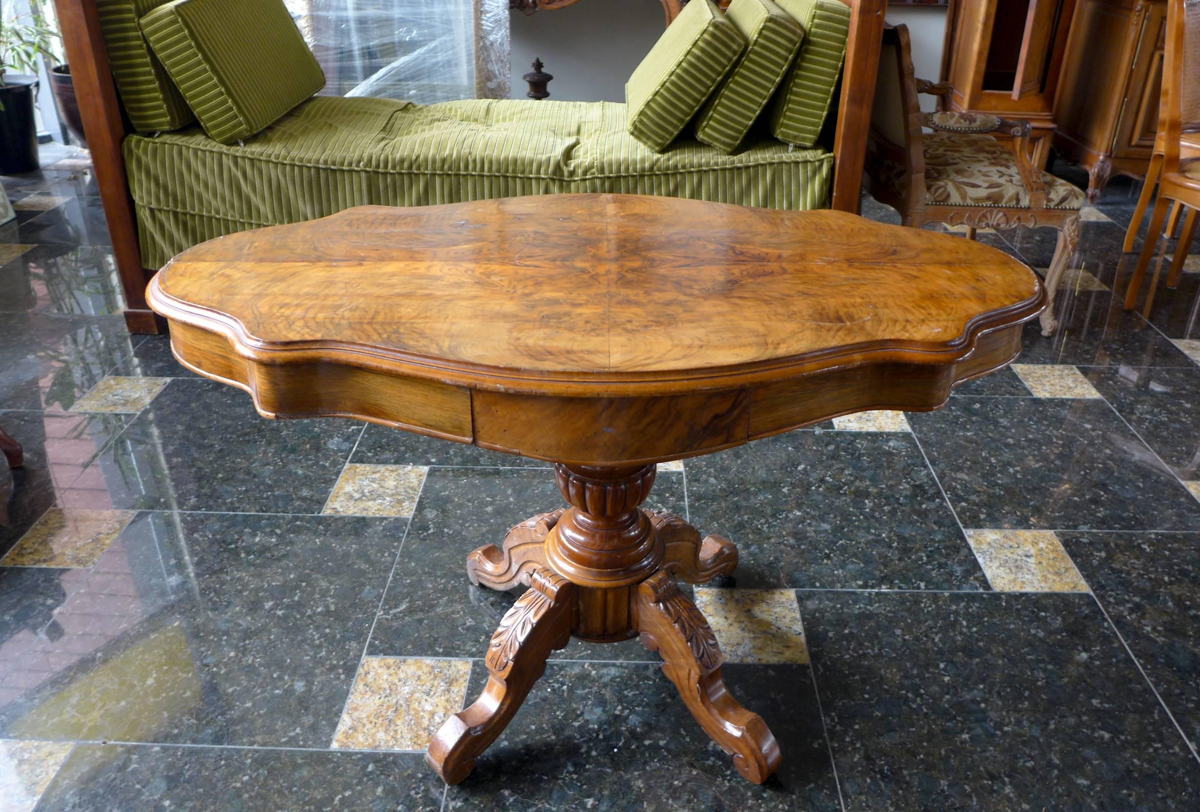 19th century Victorian style walnut centre table with beautifully figured shaped, tilt-top and moulded edge, standing on carved turned column and four carved legs with floral figures. There are two small drawers from the narrow side. The table is in