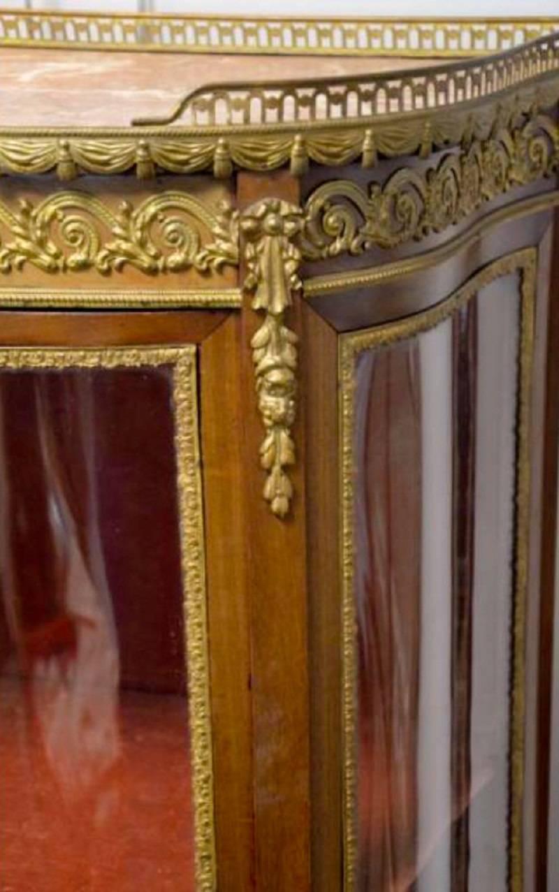 Antique French mahogany and gilded brass vitrine, pierced brass gilded gallery and inset marble, the bow fronted door opens to reveal the original faded velvet interior with two shelves, standing on cabriole legs with gilded brass mounts, original