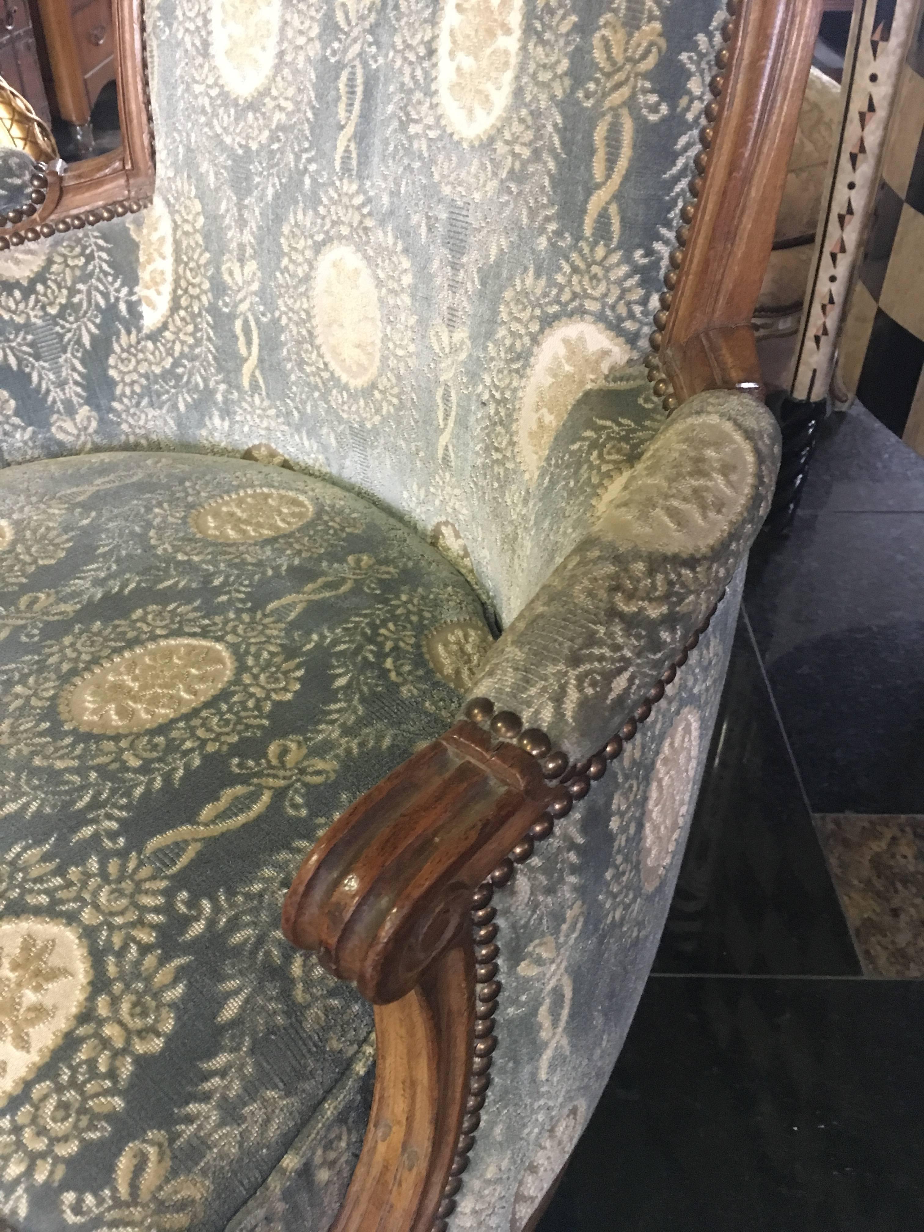 A masterfully carved 18th century Louis XVI bergère from France, resting on fluted tapered legs. The chair frame is embellished with fantastic detailed carvings, cabriolet back with rounded top. The velvet upholstery is in great condition and