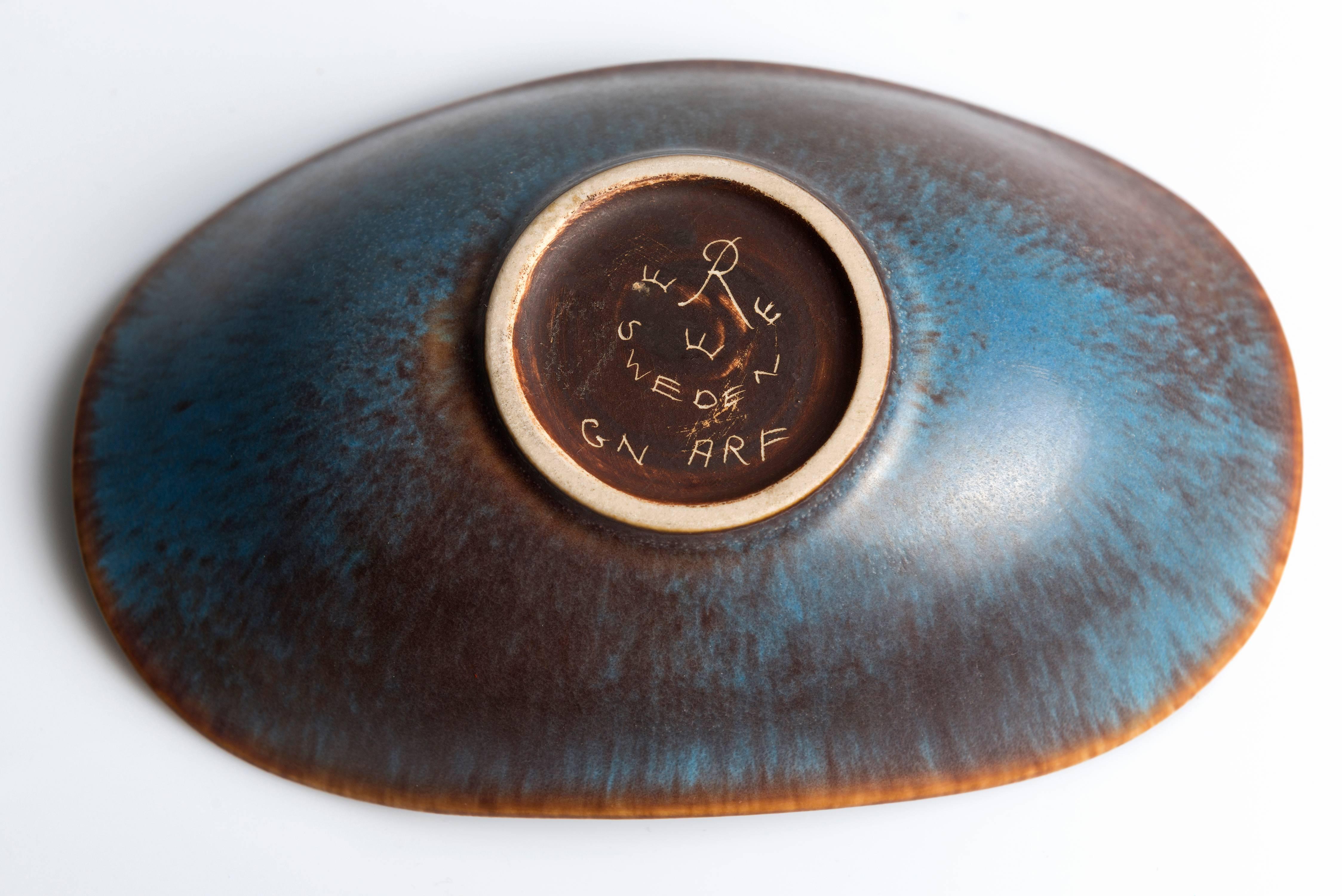 A beautiful biomorphic bowl with semi-matte mottled glaze.
Marked to the base with 'R', Three Crowns, Sweden, the model number and the designer's monogram. In fine vintage condition.