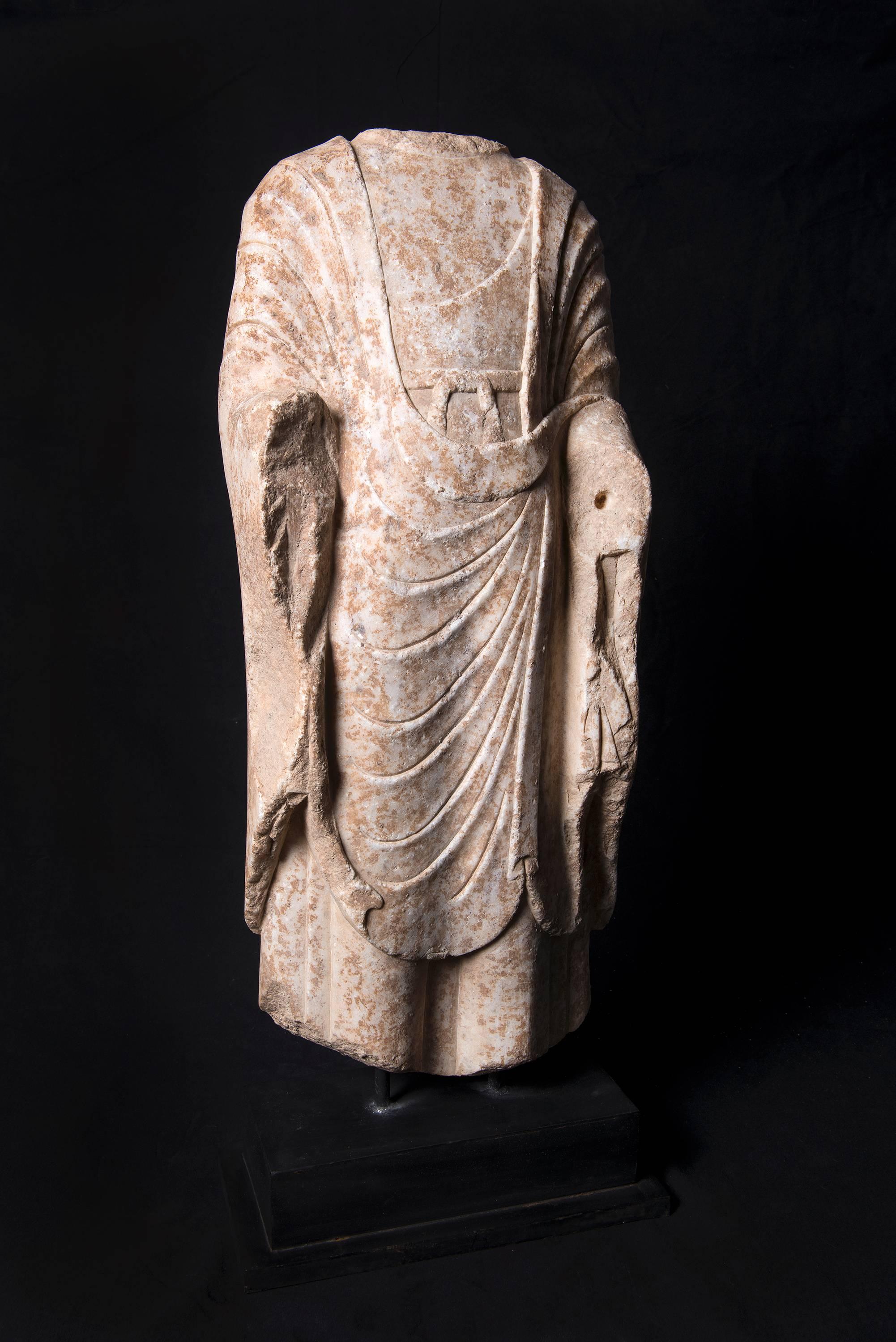 An impeccable example of ancient Chinese art. This substantial sculpture from the Tang dynasty (618-907 C.E.) is rendered in white marble. The torso of a Buddha draped in ceremonial robes, finished with an expert hand and exacting